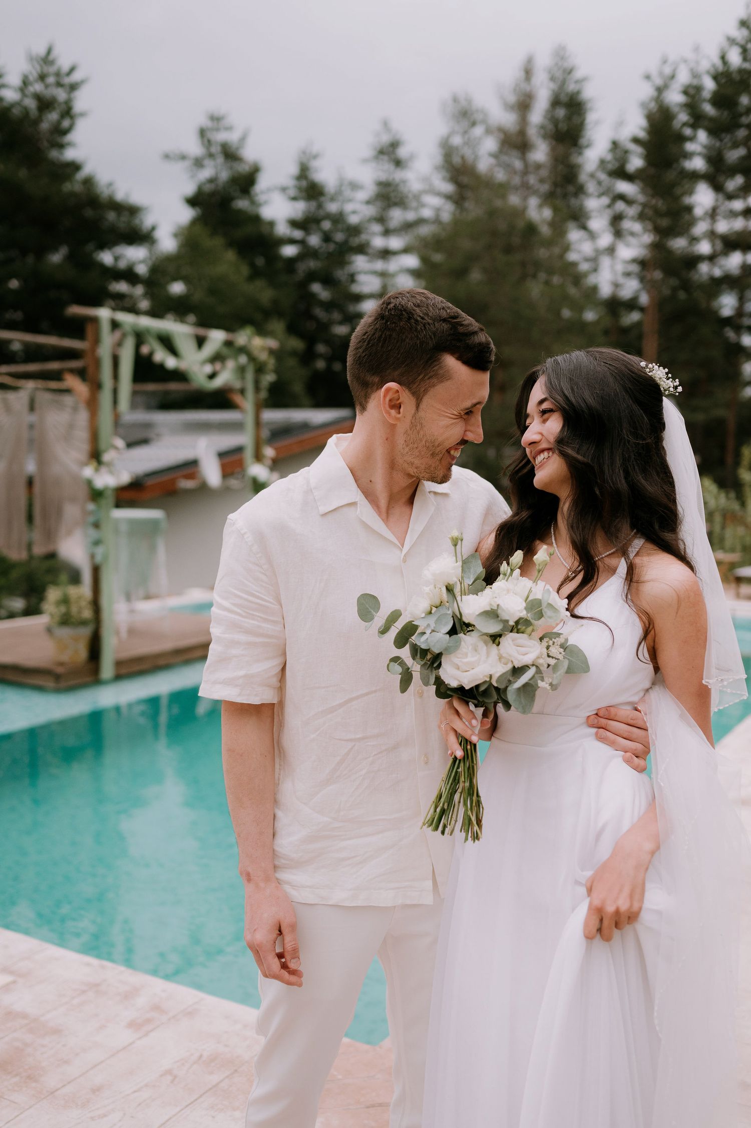 Intimate wedding portraits taken beside a beautiful turquoise pool on a cloudy day.