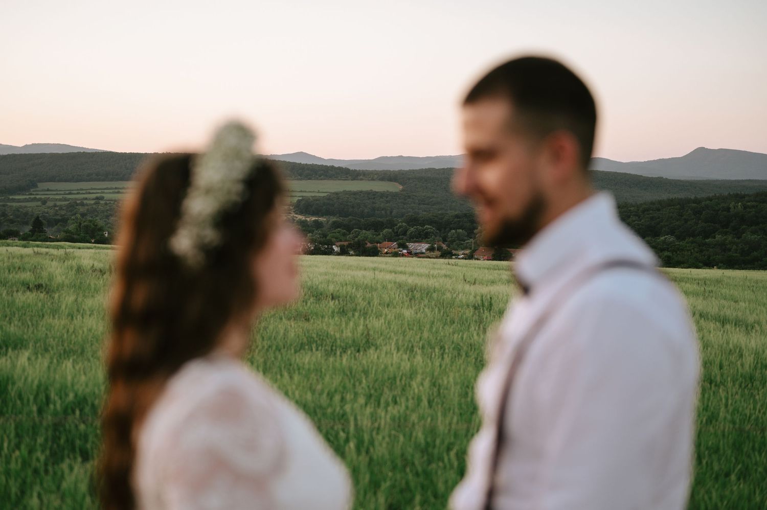 Romantic sunset portrait in a meadow with rolling hills in the background.