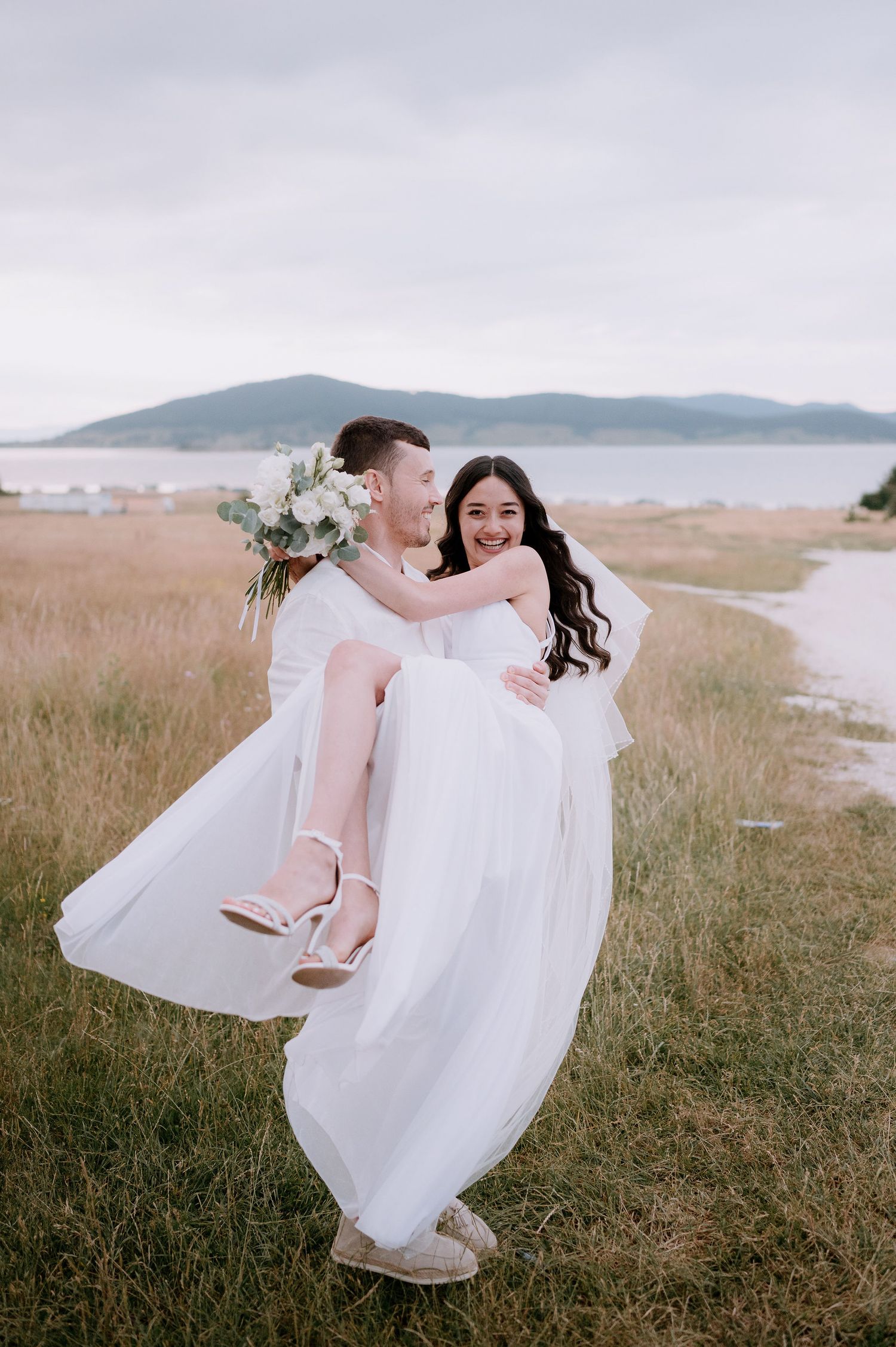 A romantic wedding dance captured in a meadow with mountains and ocean views.