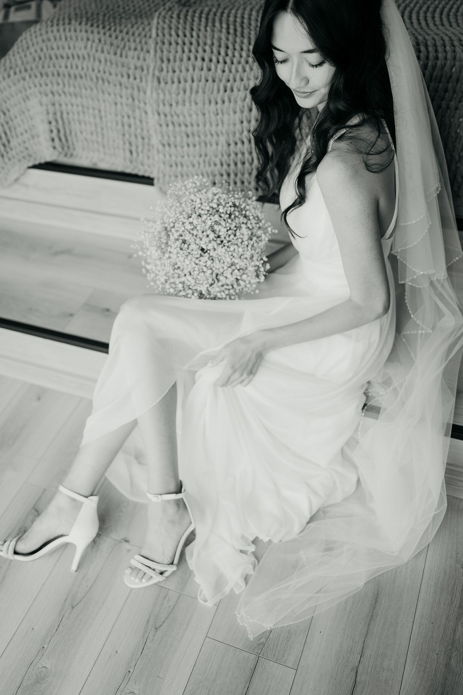 Black and white artistic bridal photos showing flowing dress details on wooden floor.