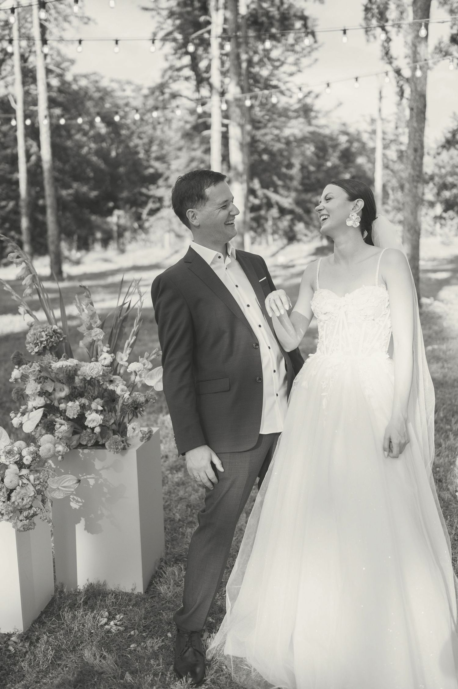 Black and white photo of a couple sharing a joyful moment during their outdoor forest wedding ceremony.