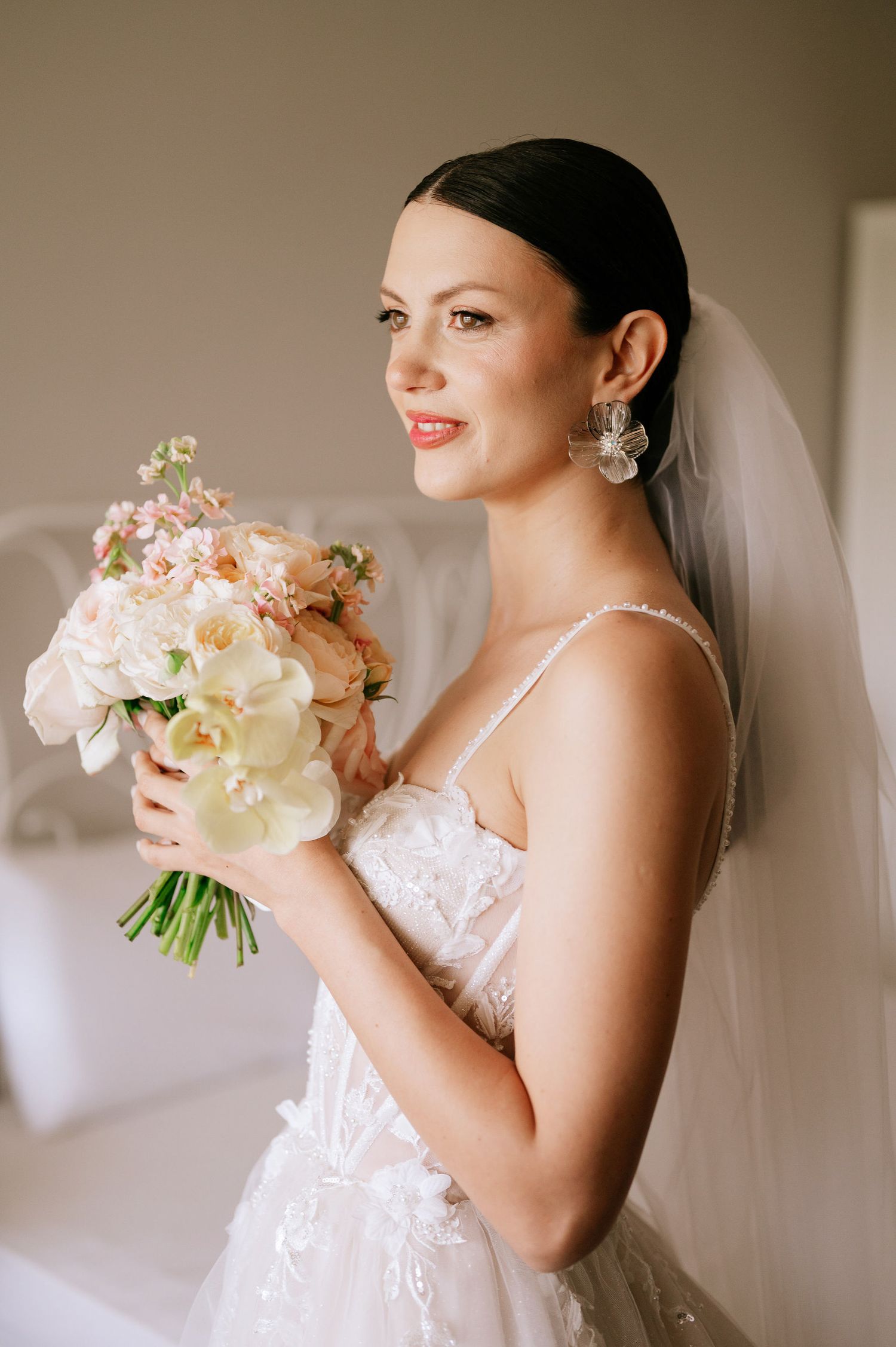Joyful bridal moment captured with flowing white dress and fresh floral arrangement.