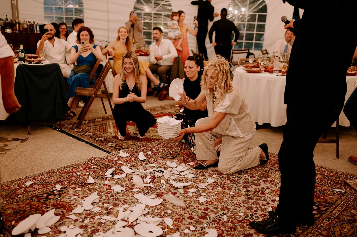 Wedding reception scene showing guests dancing on a decorative carpet.