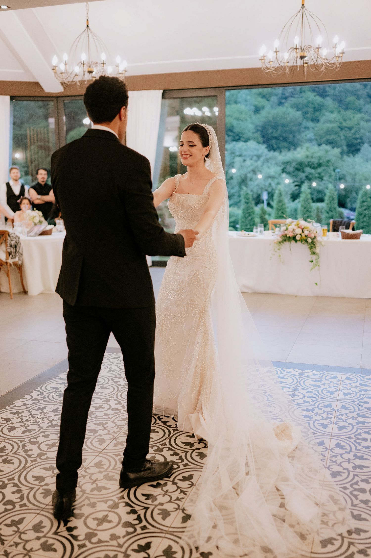 Elegant ballroom dance floor with ornate patterned tiles and chandeliers overhead.