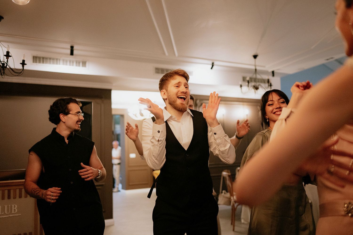 People dancing and celebrating in an indoor venue with warm lighting.