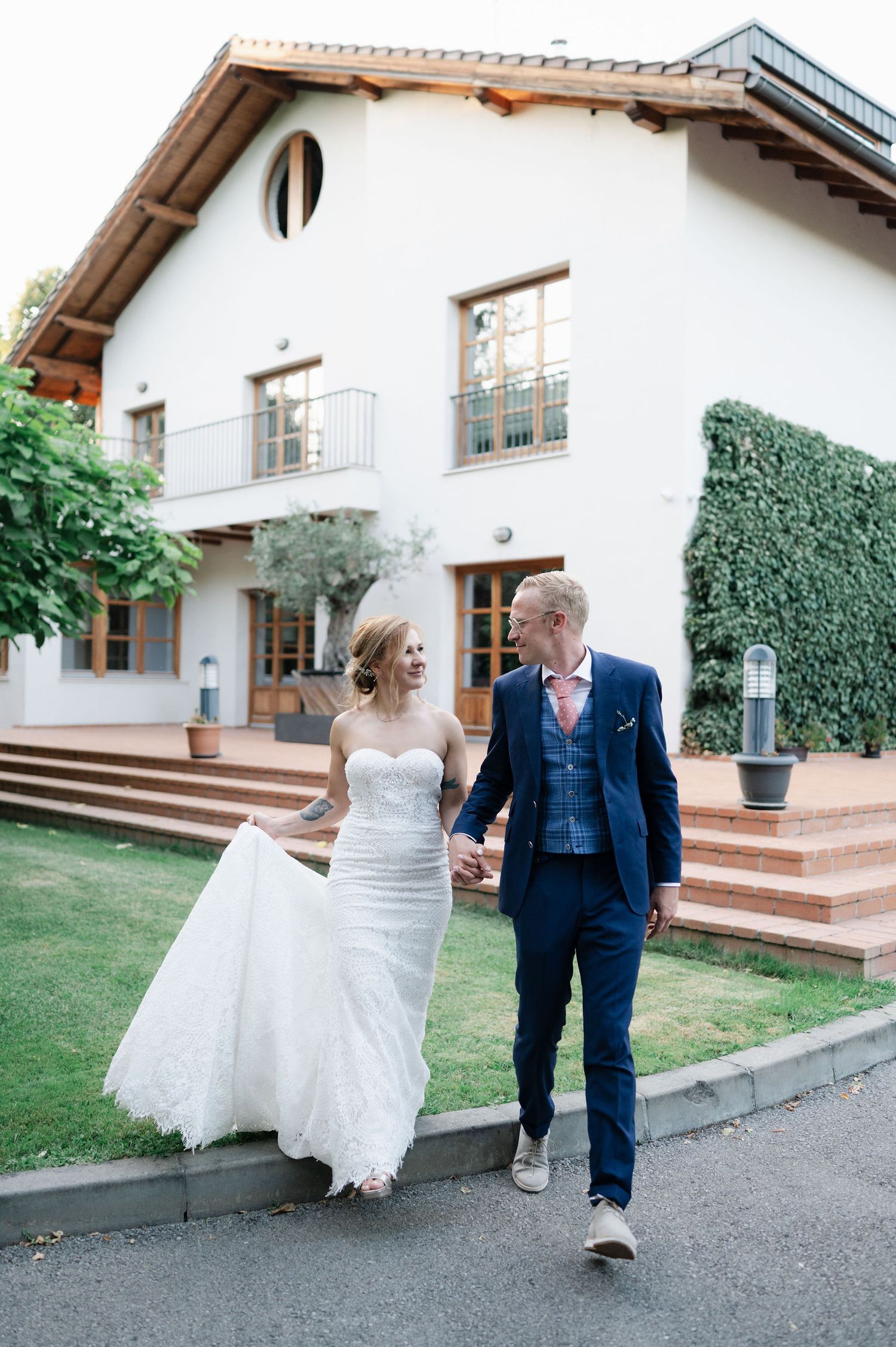 Wedding couple shares playful moments outside a white villa with wooden steps.