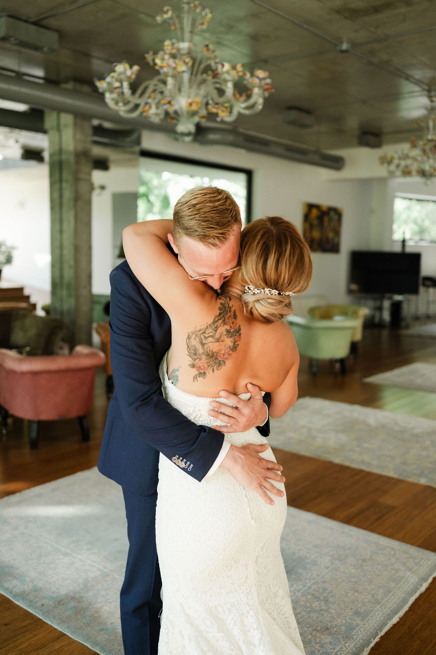 An emotional wedding moment captured in a room with hardwood floors and chandeliers.