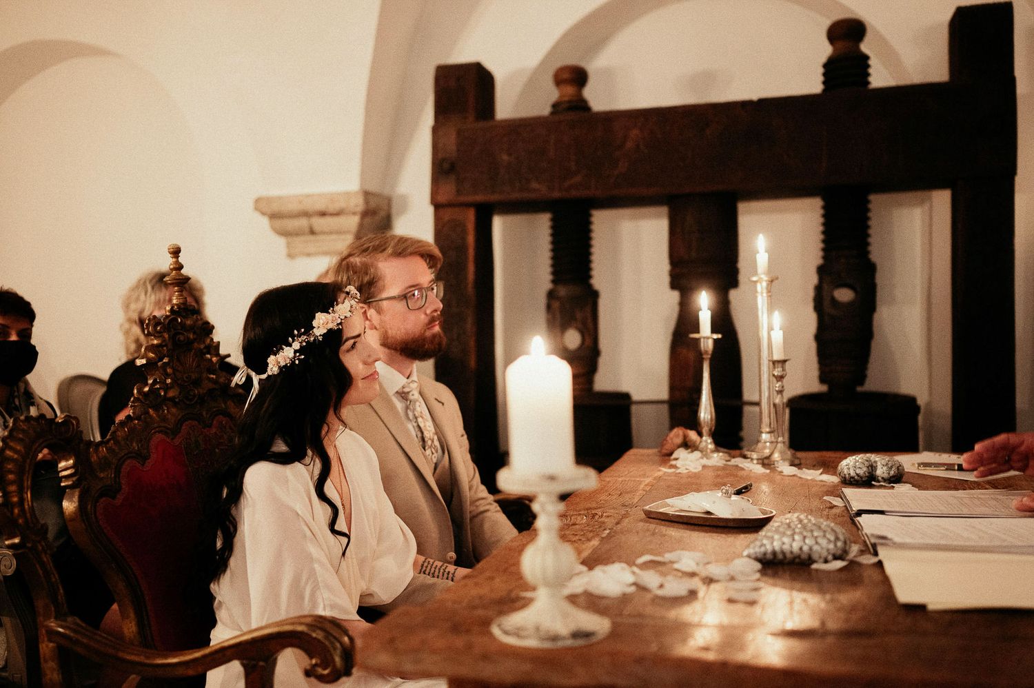 Atmospheric dining scene with candlelit wooden table in a historic interior setting.