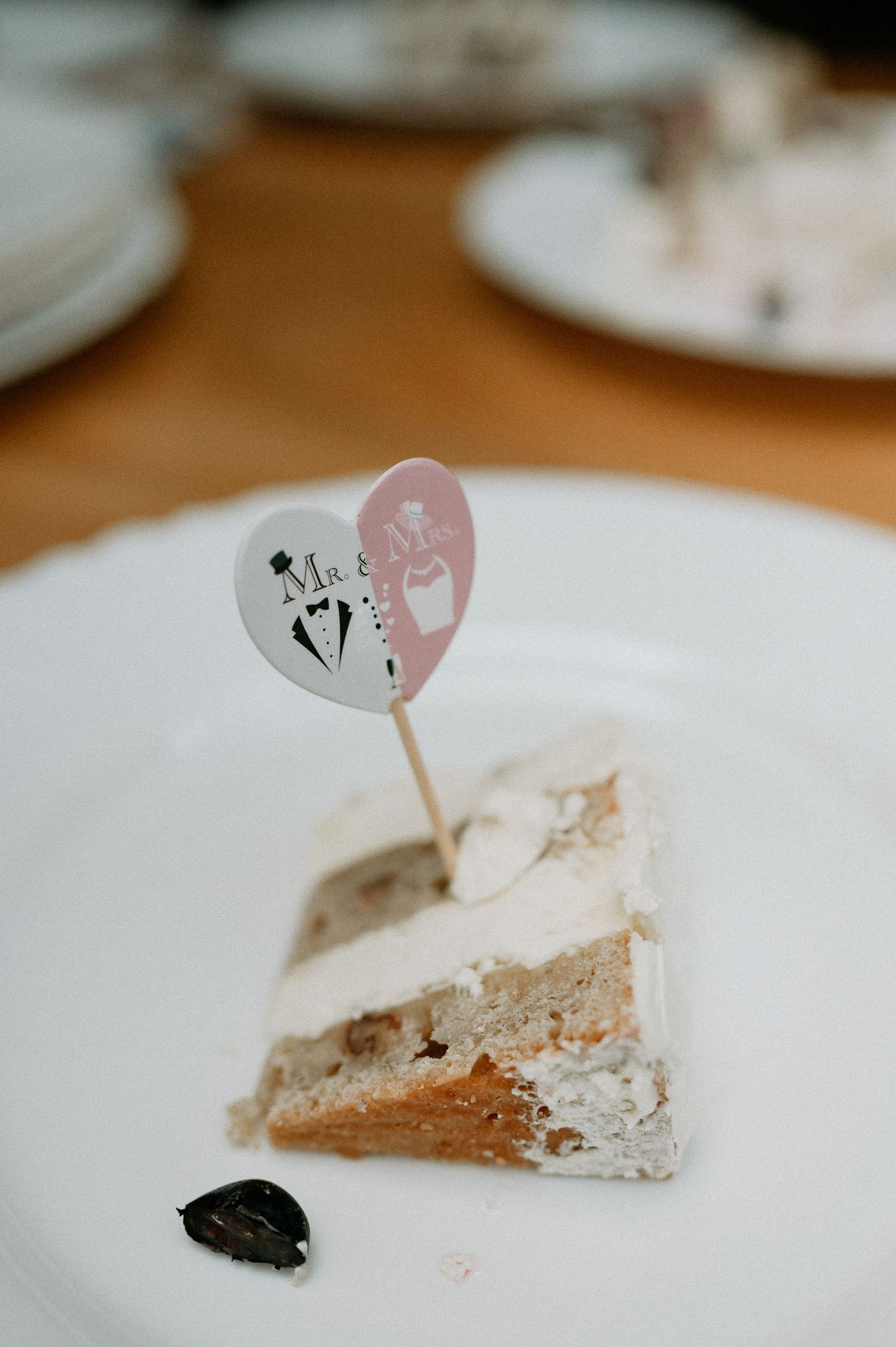 A slice of wedding cake with a decorative heart-shaped topper on a white plate.