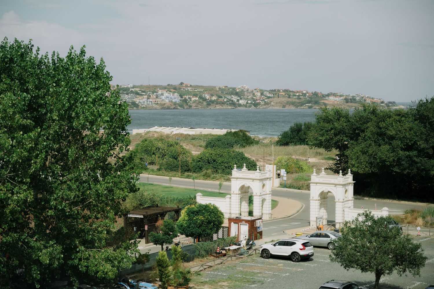 Scenic view of white architectural gates and buildings against green landscape.