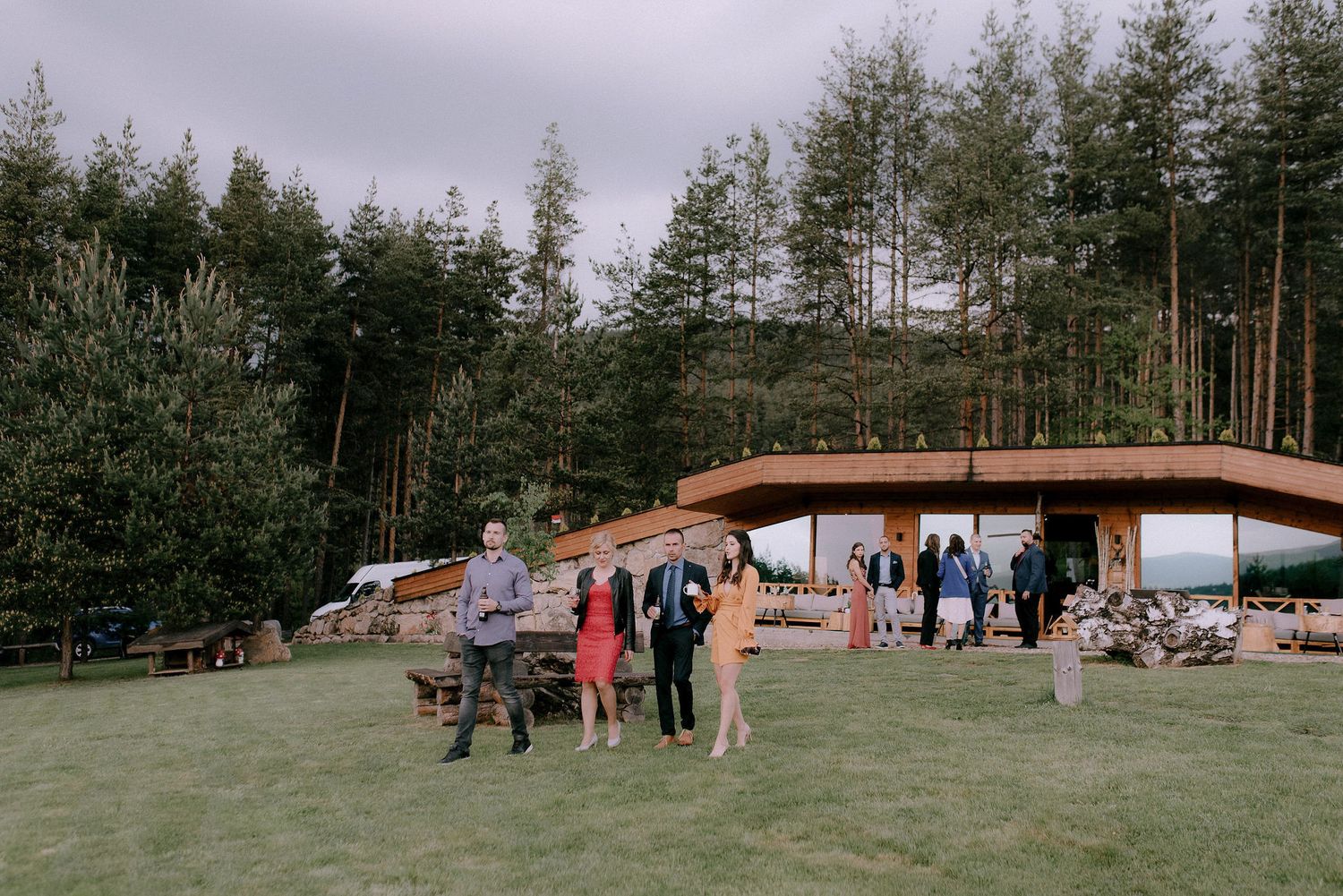 Panoramic view of a rustic outdoor venue with A-frame cabins nestled among pine trees.