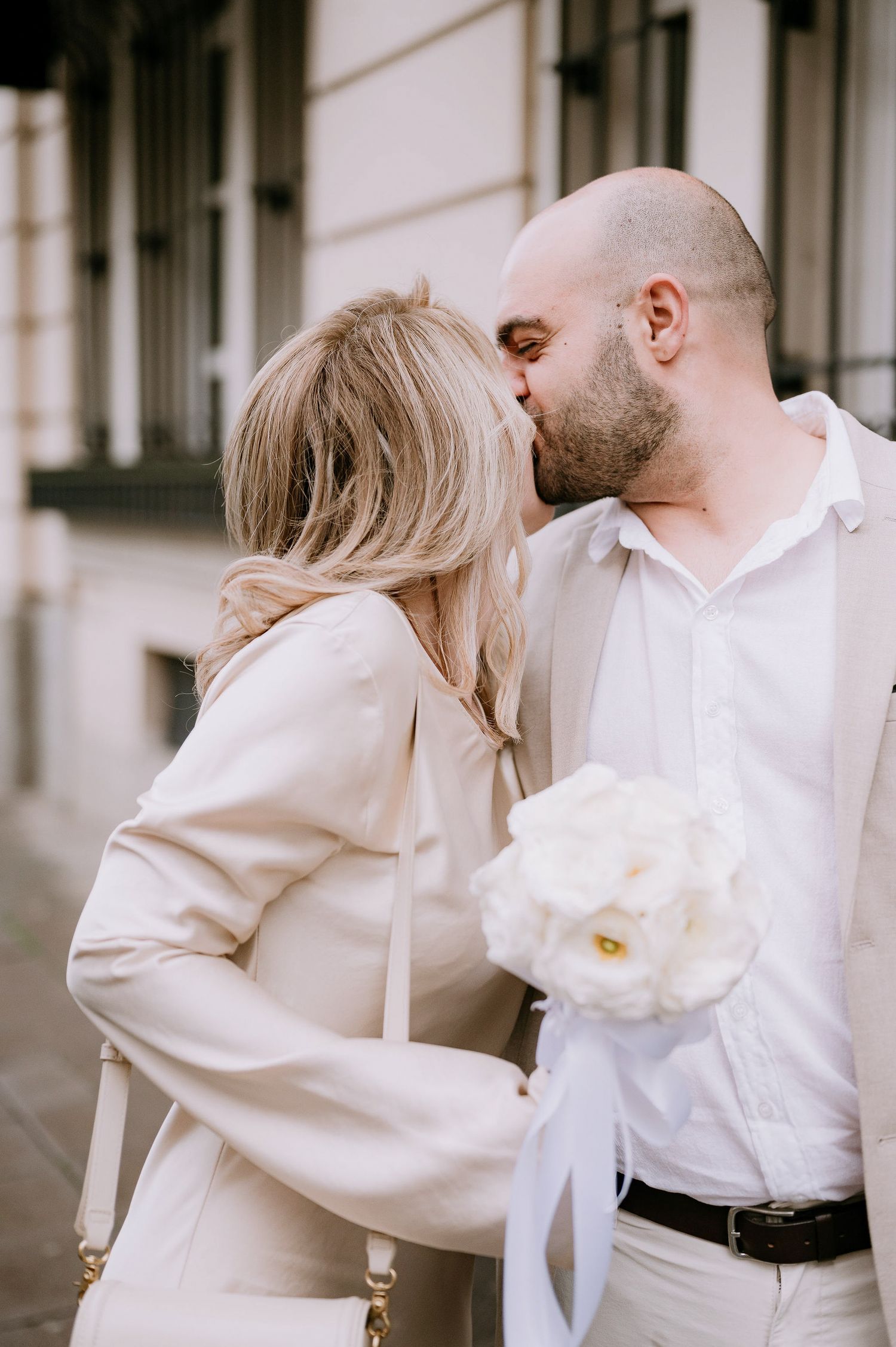 Intimate moment between couple wearing coordinated cream colored outfits.