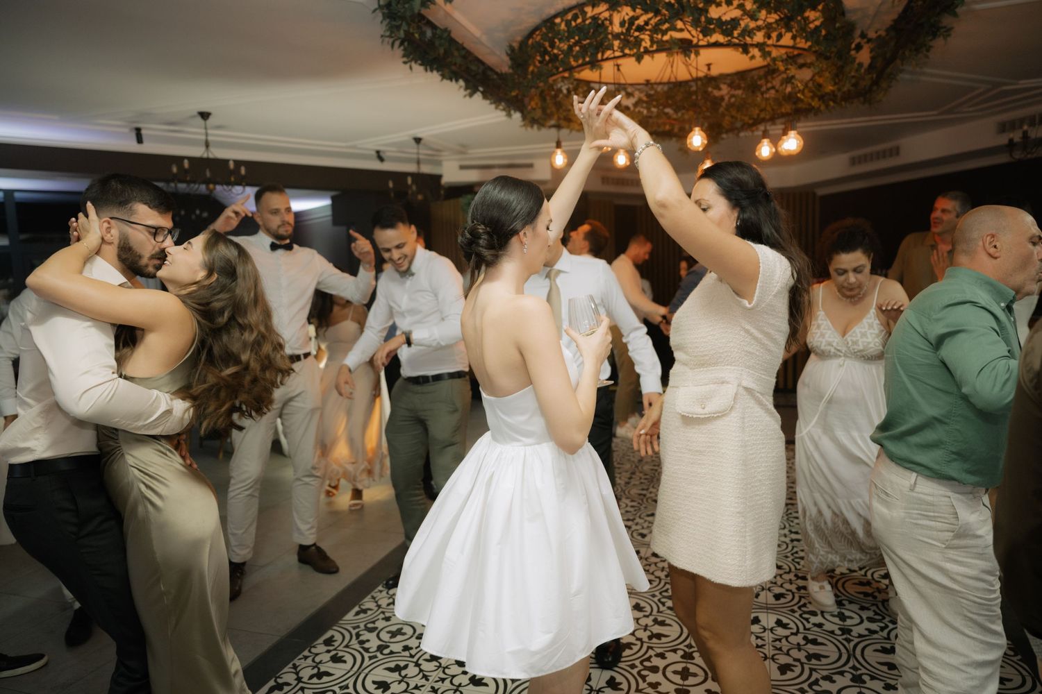 Wedding guests dancing together on the dance floor during a lively reception celebration.