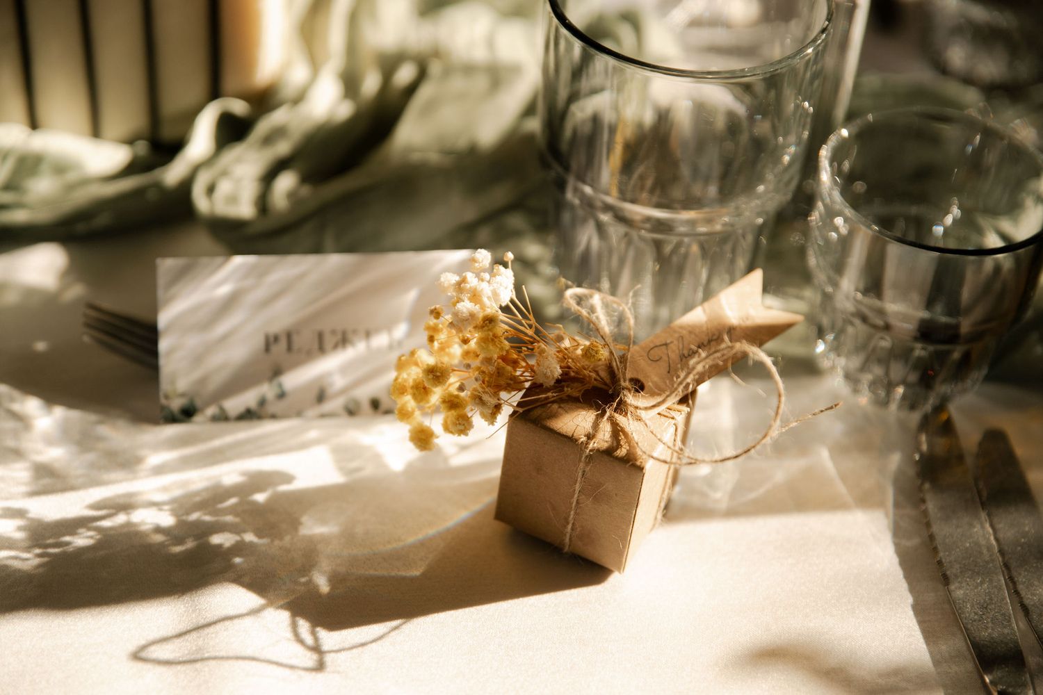 Elegant table settings with glassware and gold accents under natural lighting at a wedding reception.