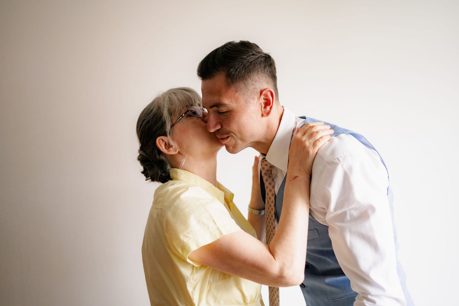 A couple shares a tender romantic moment in a bright, minimalist setting wearing casual and formal attire.