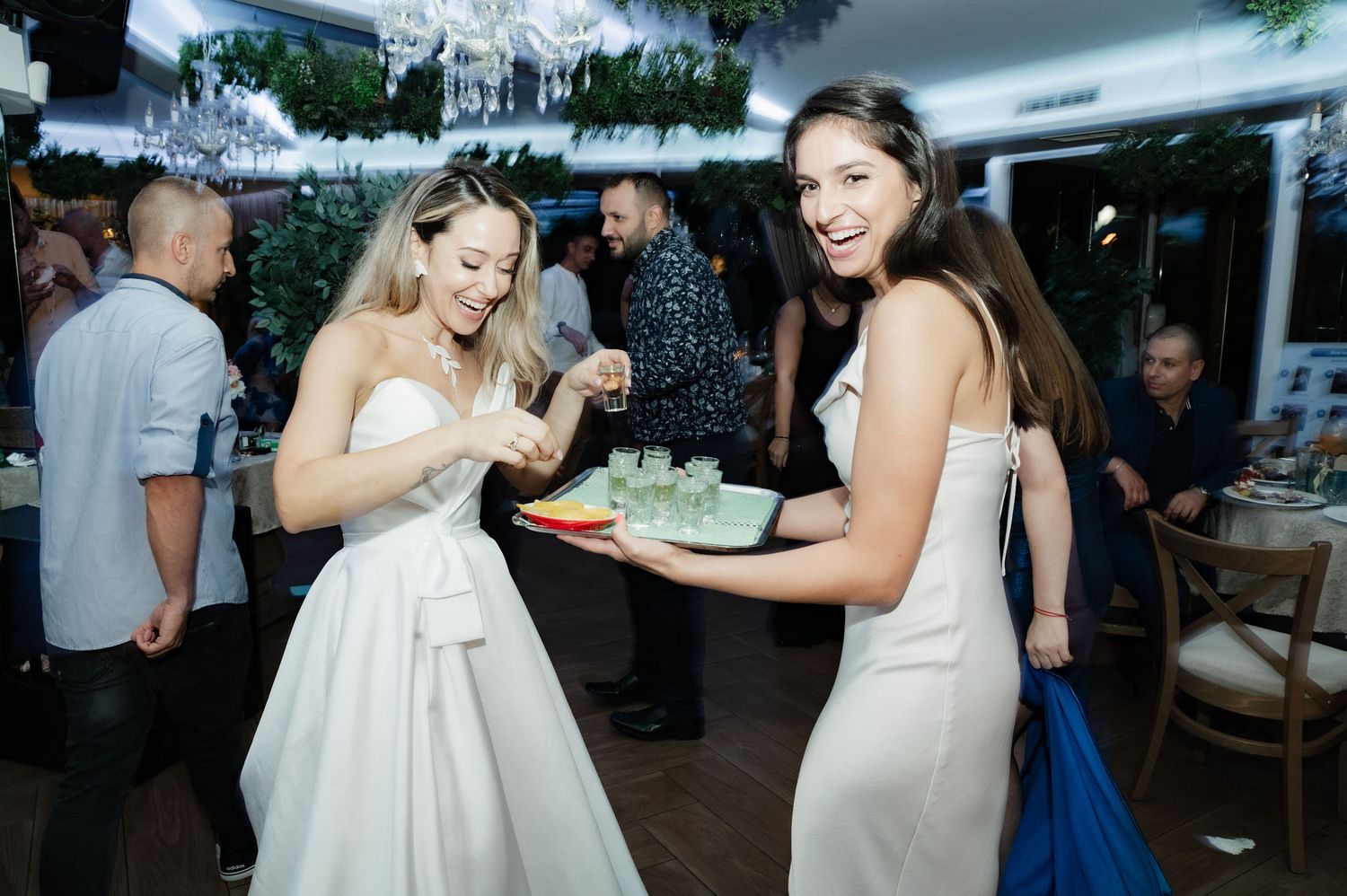 Wedding guests dance and celebrate together under a crystal chandelier at an elegant indoor reception venue.