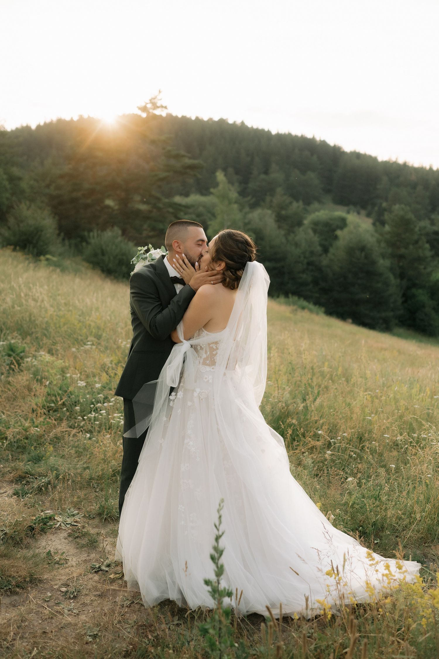 A romantic sunset wedding photo series shows a couple embracing in a golden meadow with flowing white dress and veil.