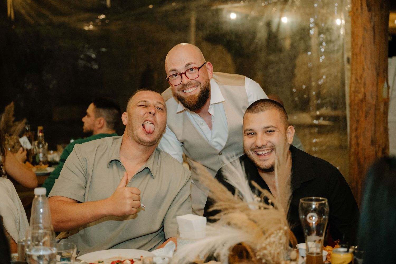 A group celebrates and socializes at a rustic wooden bar with drinks and laughter.