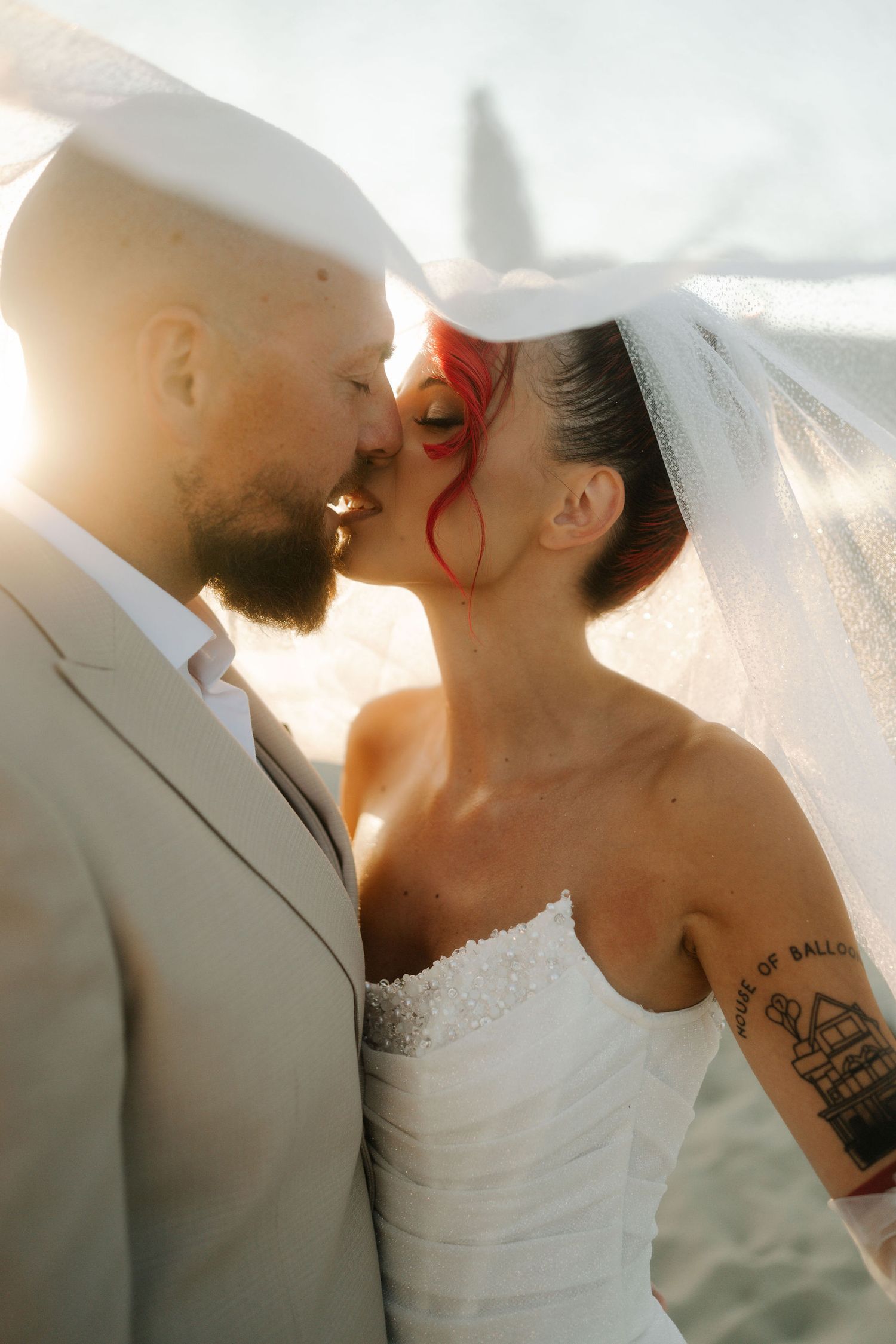 A romantic wedding couple shares an intimate kiss during golden hour sunlight.
