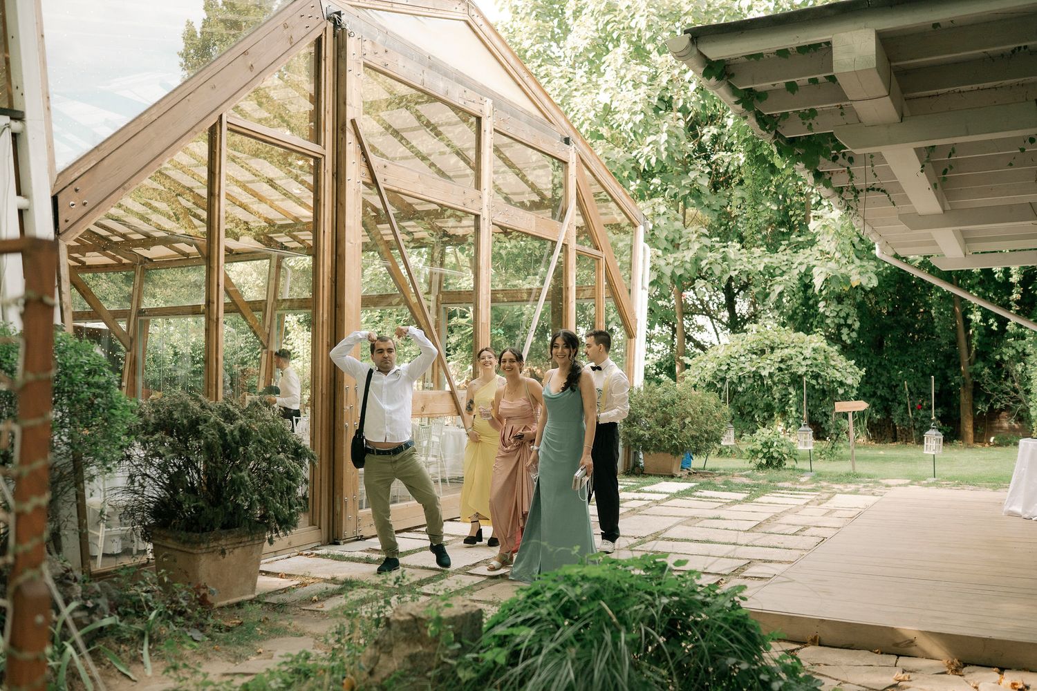 A covered wooden walkway with natural bamboo and greenery surrounds the path through a tropical garden setting.