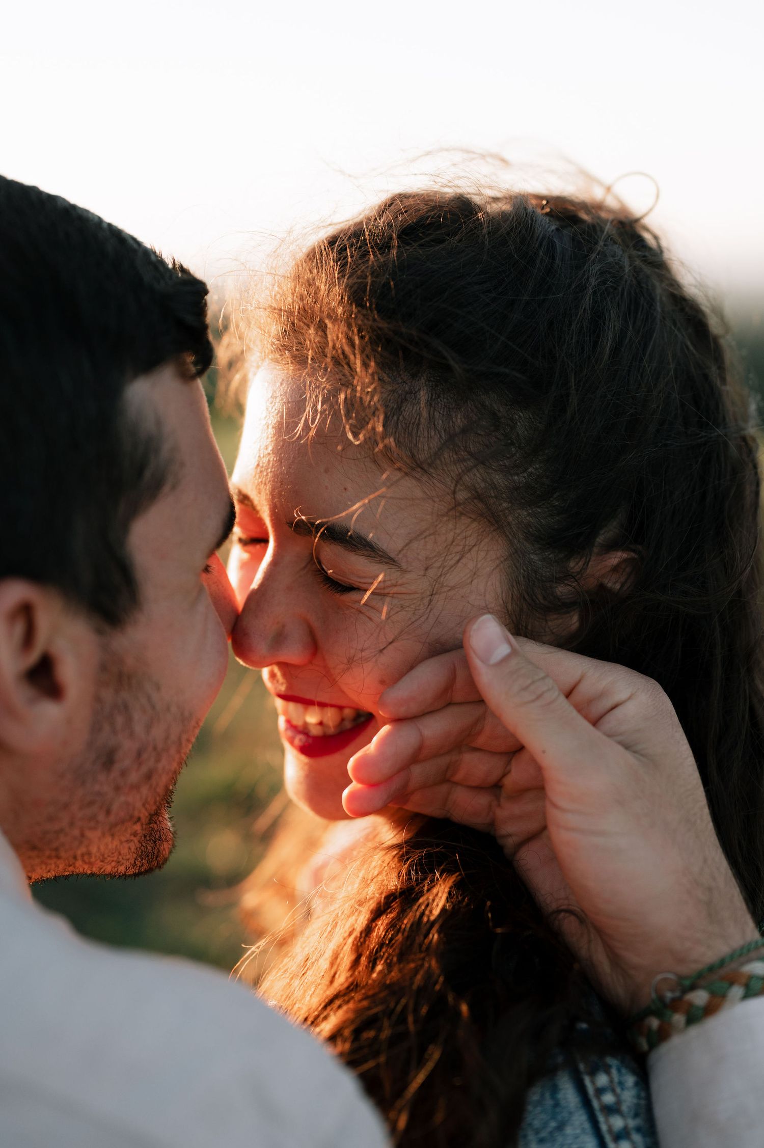 Intimate couple sharing a tender moment at sunset with warm golden light illuminating their faces.