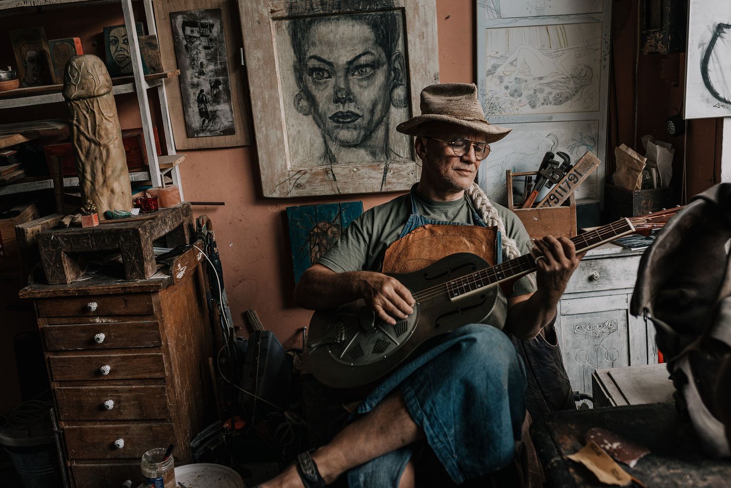 Artistic workspace with portrait sketches hanging on salmon-colored walls.
