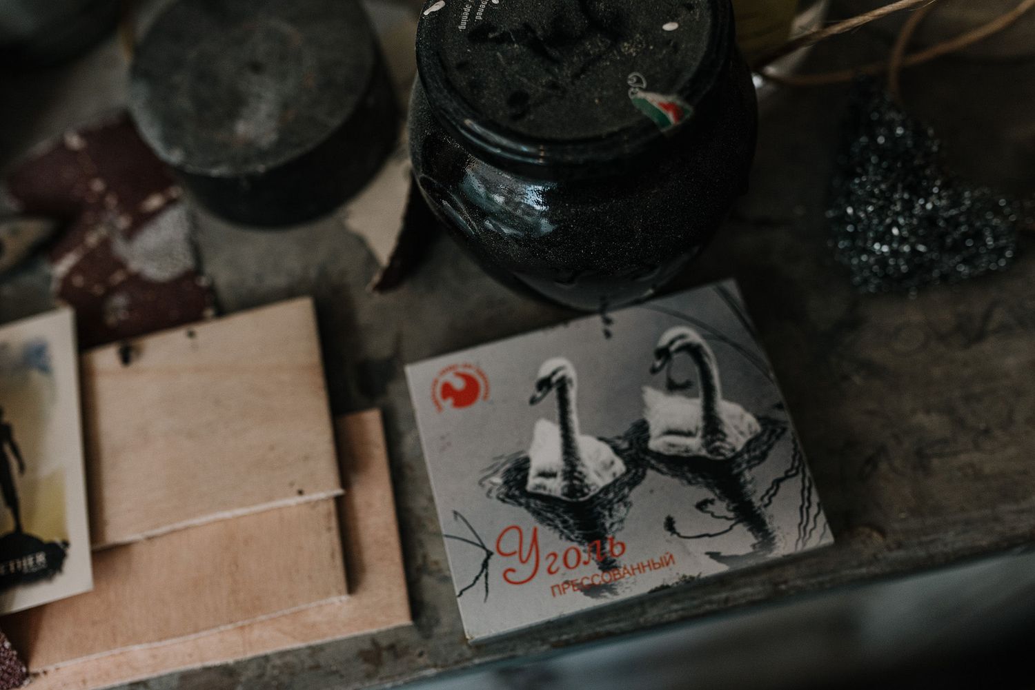 Dark moody photograph of art supplies and tools on a wooden workspace.