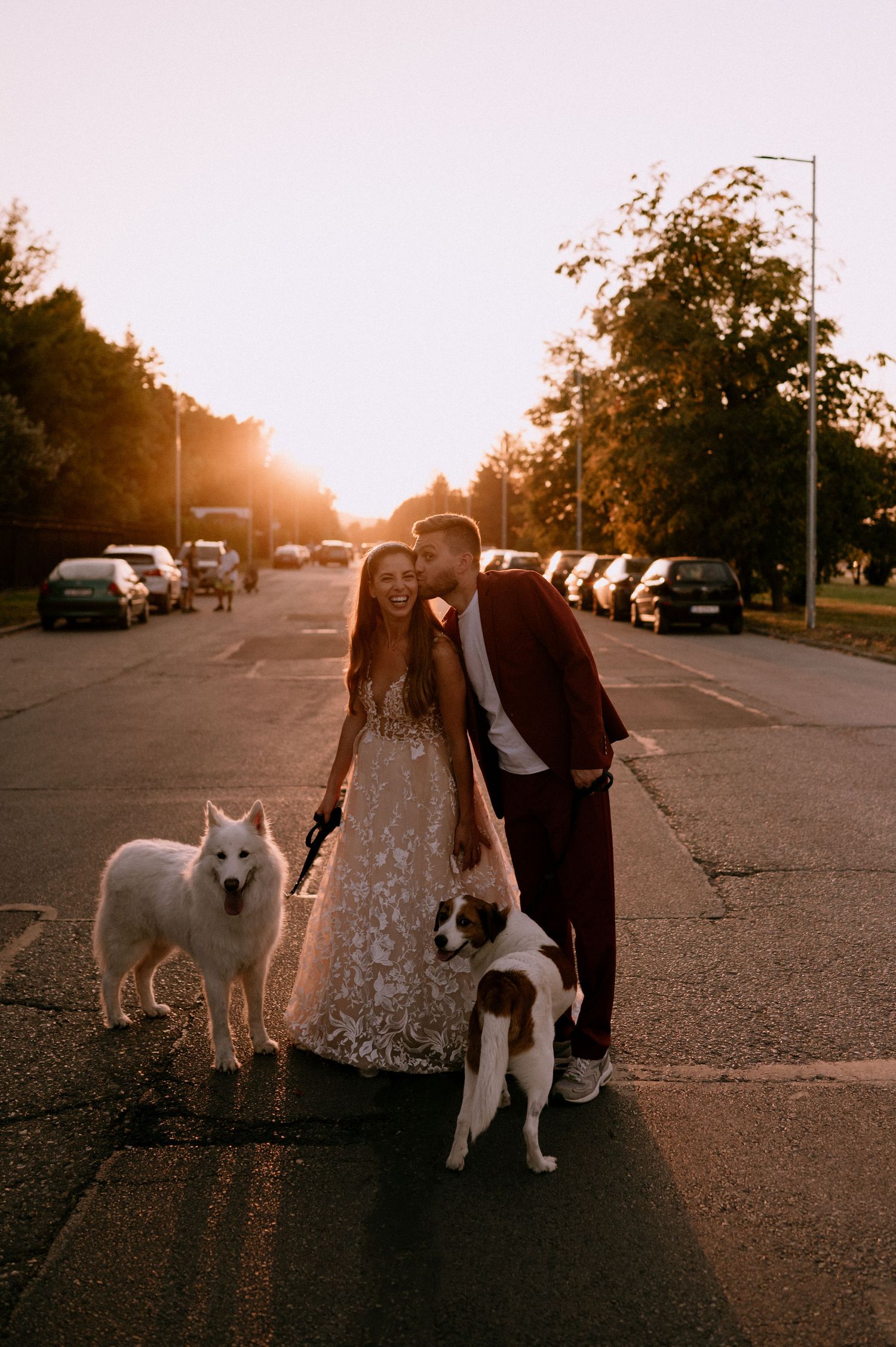 A sunset photoshoot featuring a couple and their white dog in a parking lot.