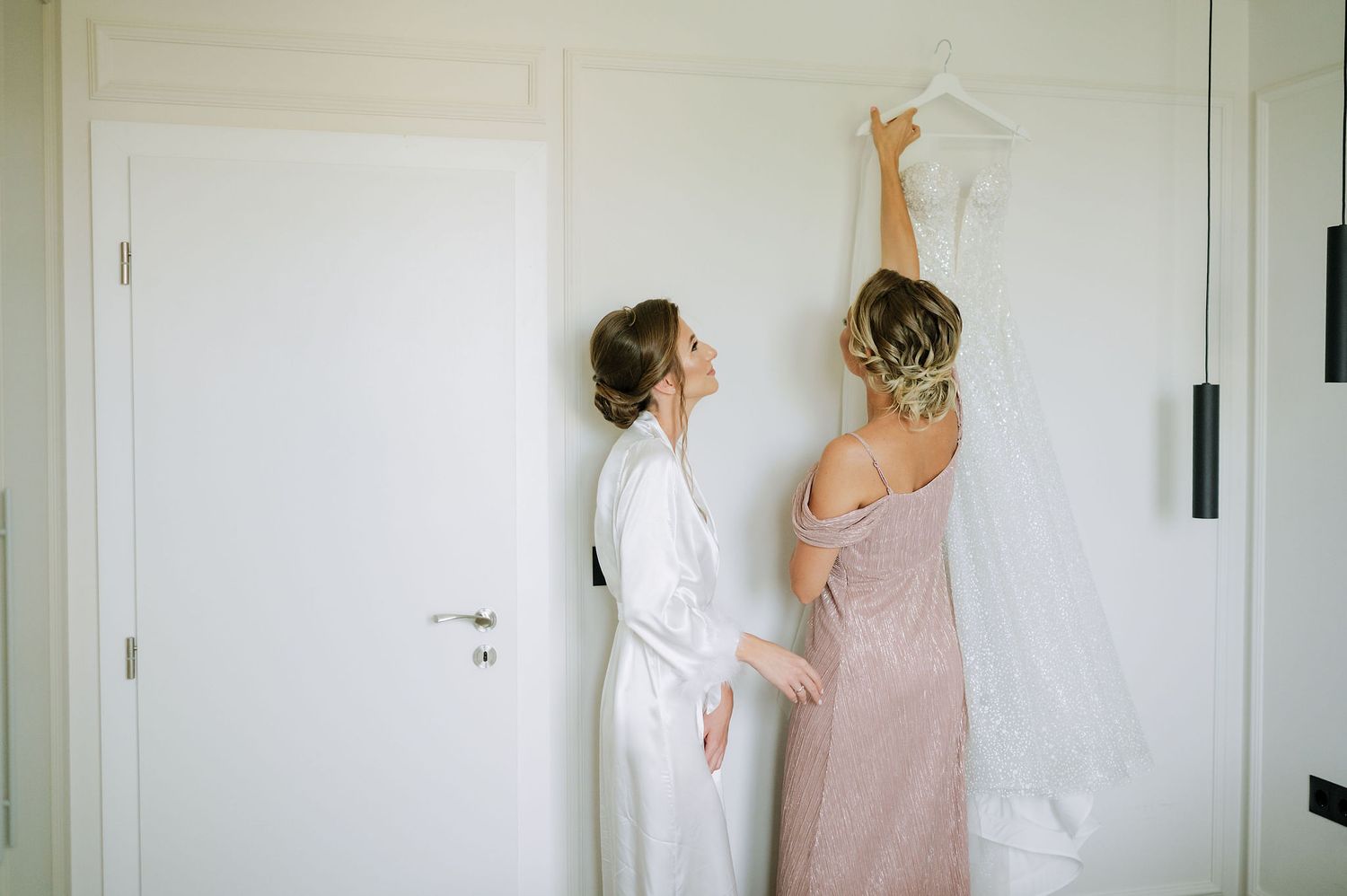 A wedding dress being adjusted in a minimalist white room.