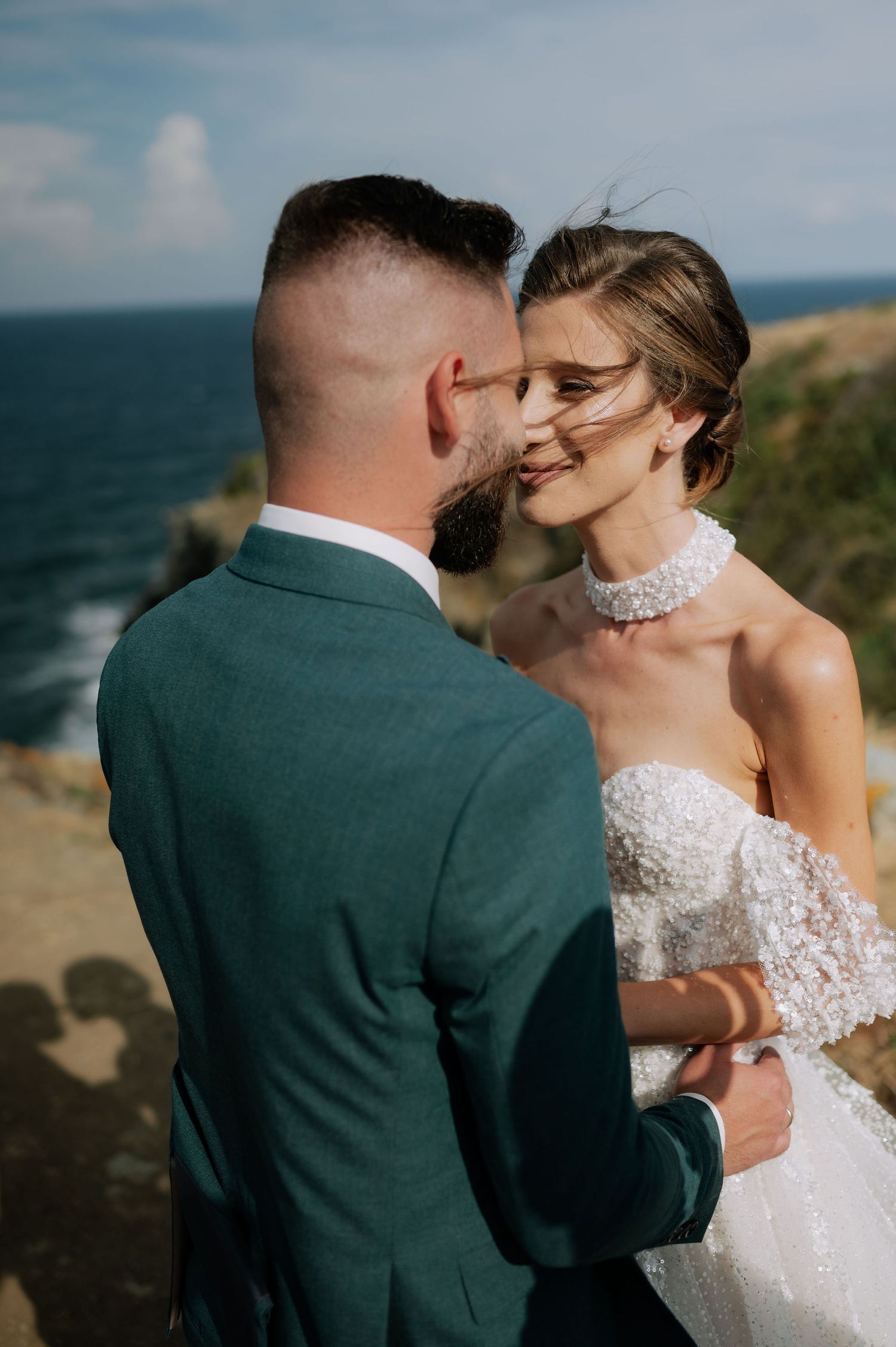 A tender wedding moment photographed on a scenic coastal overlook with ocean views.