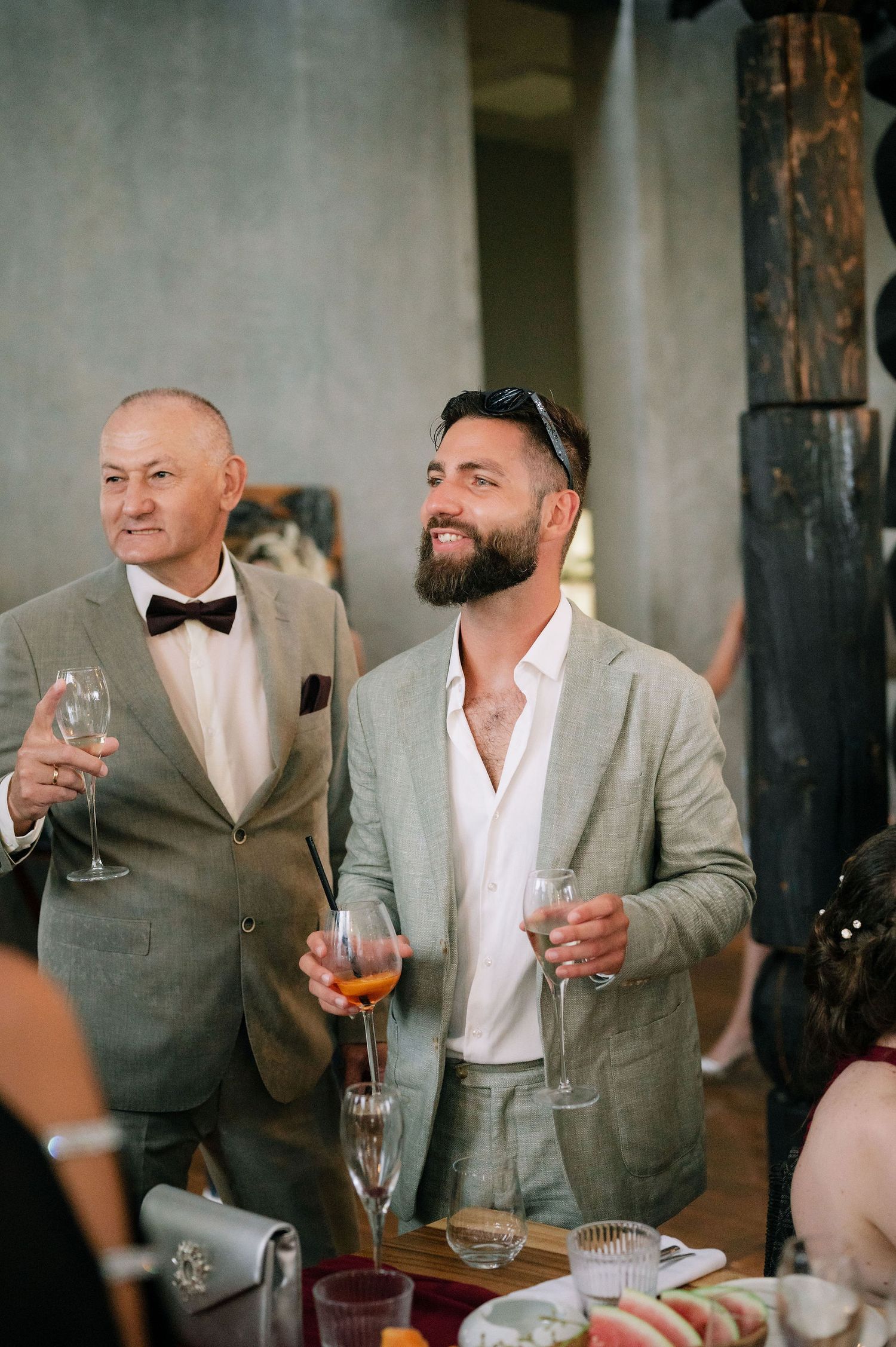 Two guests in formal attire share a moment while holding champagne glasses at an event.
