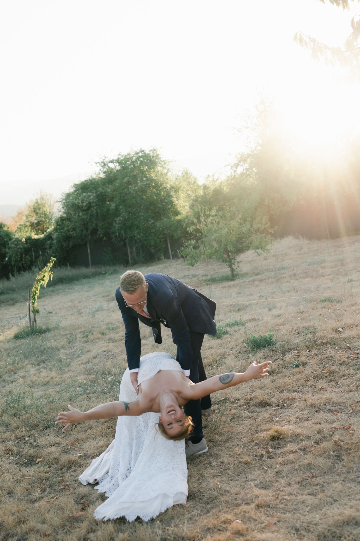 A romantic wedding dip pose captured in golden hour lighting on a hillside.