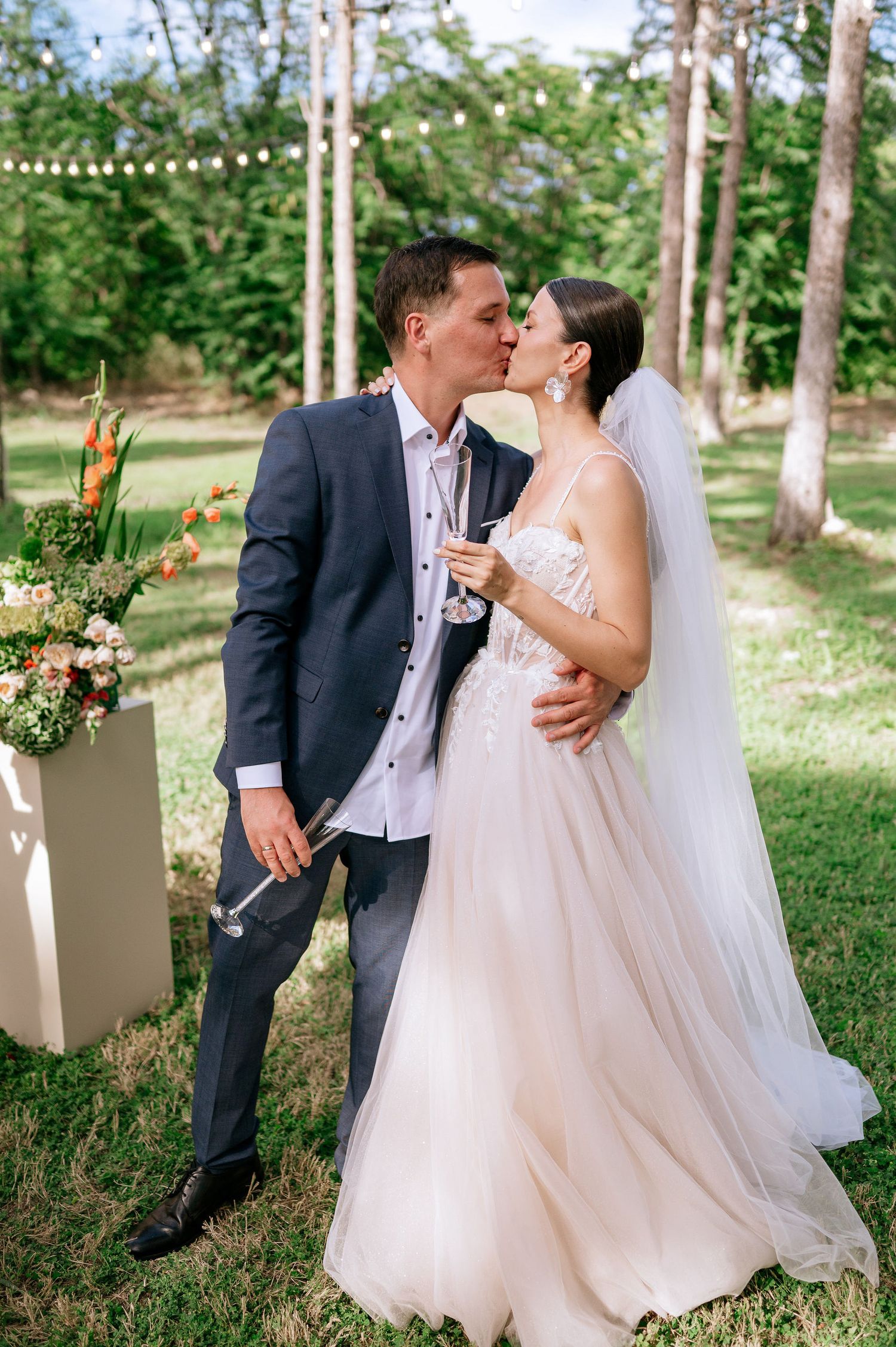 Intimate wedding moment captured in a natural forest setting with decorative elements.