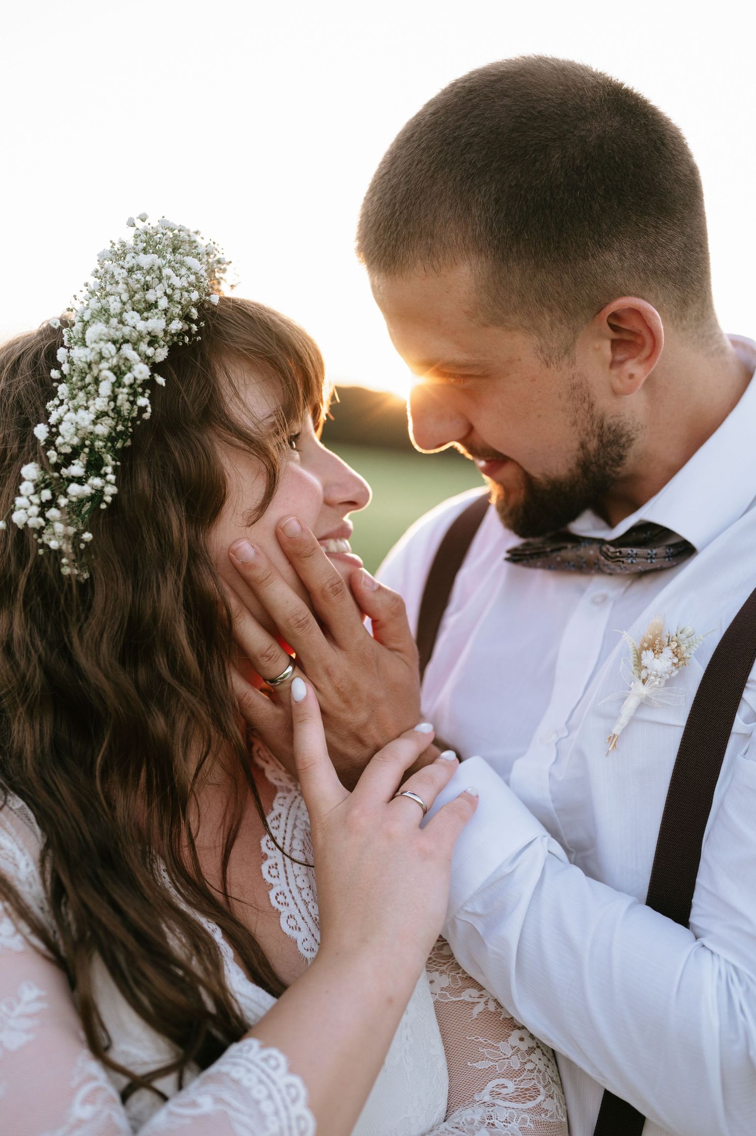 Intimate moment between newlyweds at sunset with bride wearing baby's breath crown.