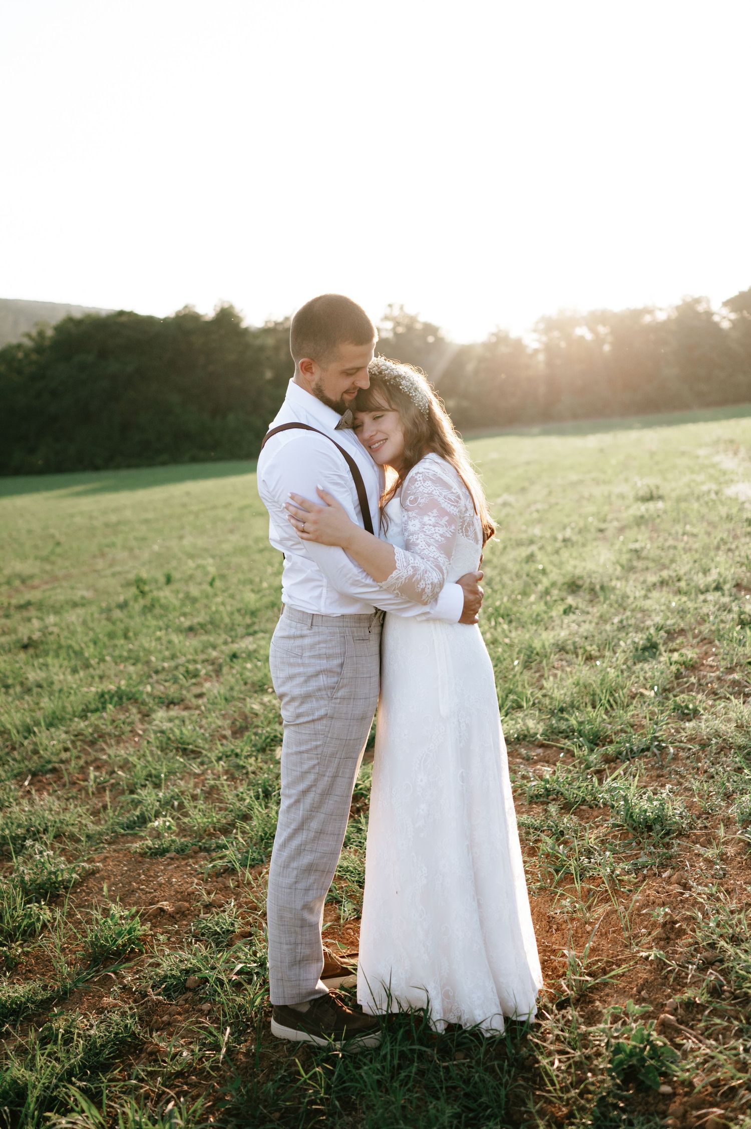 A sweet embrace between newlyweds in a golden-lit field during their wedding photoshoot.