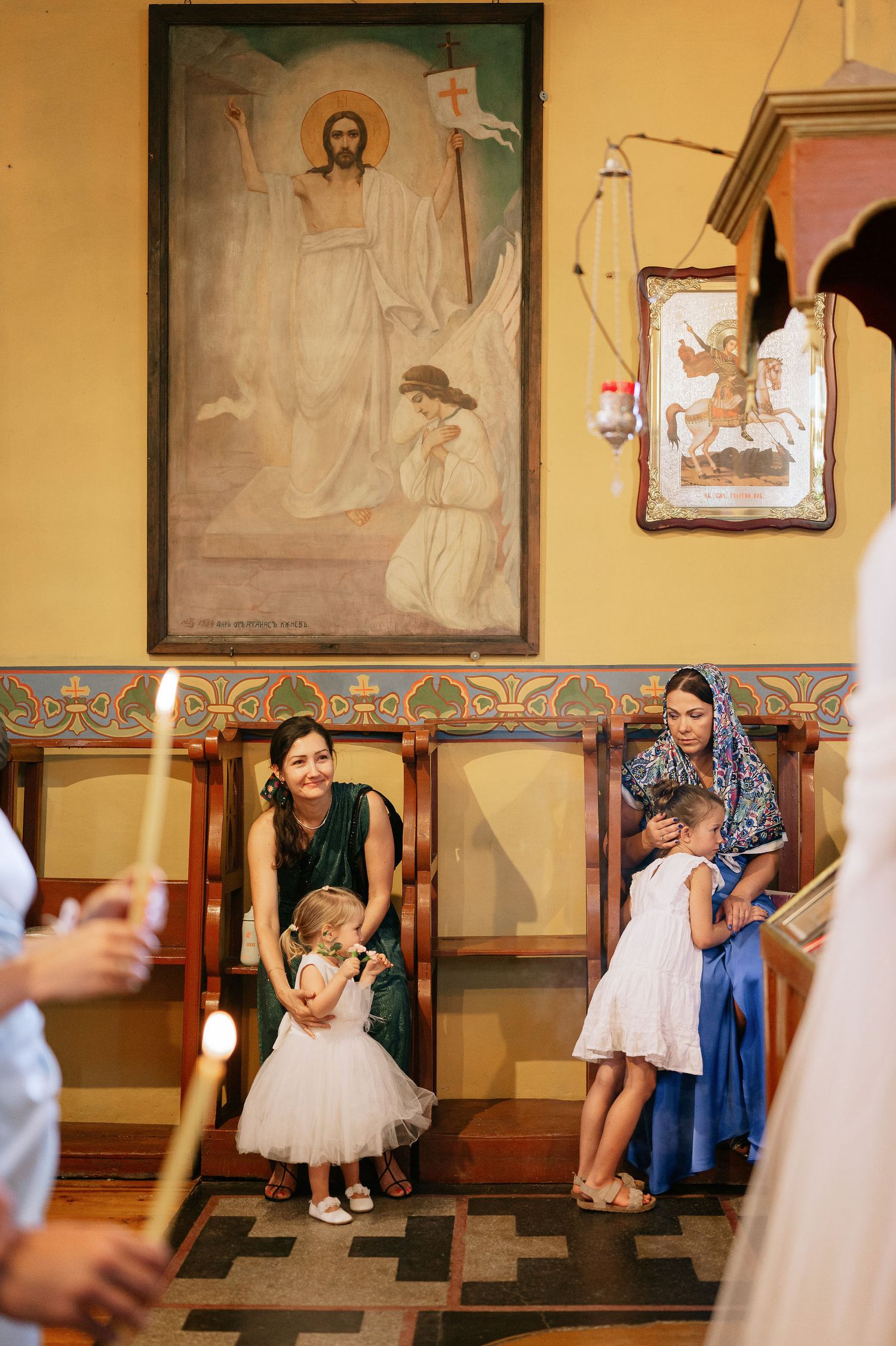 Church interior with religious artwork and icons displayed on yellow walls during ceremony.