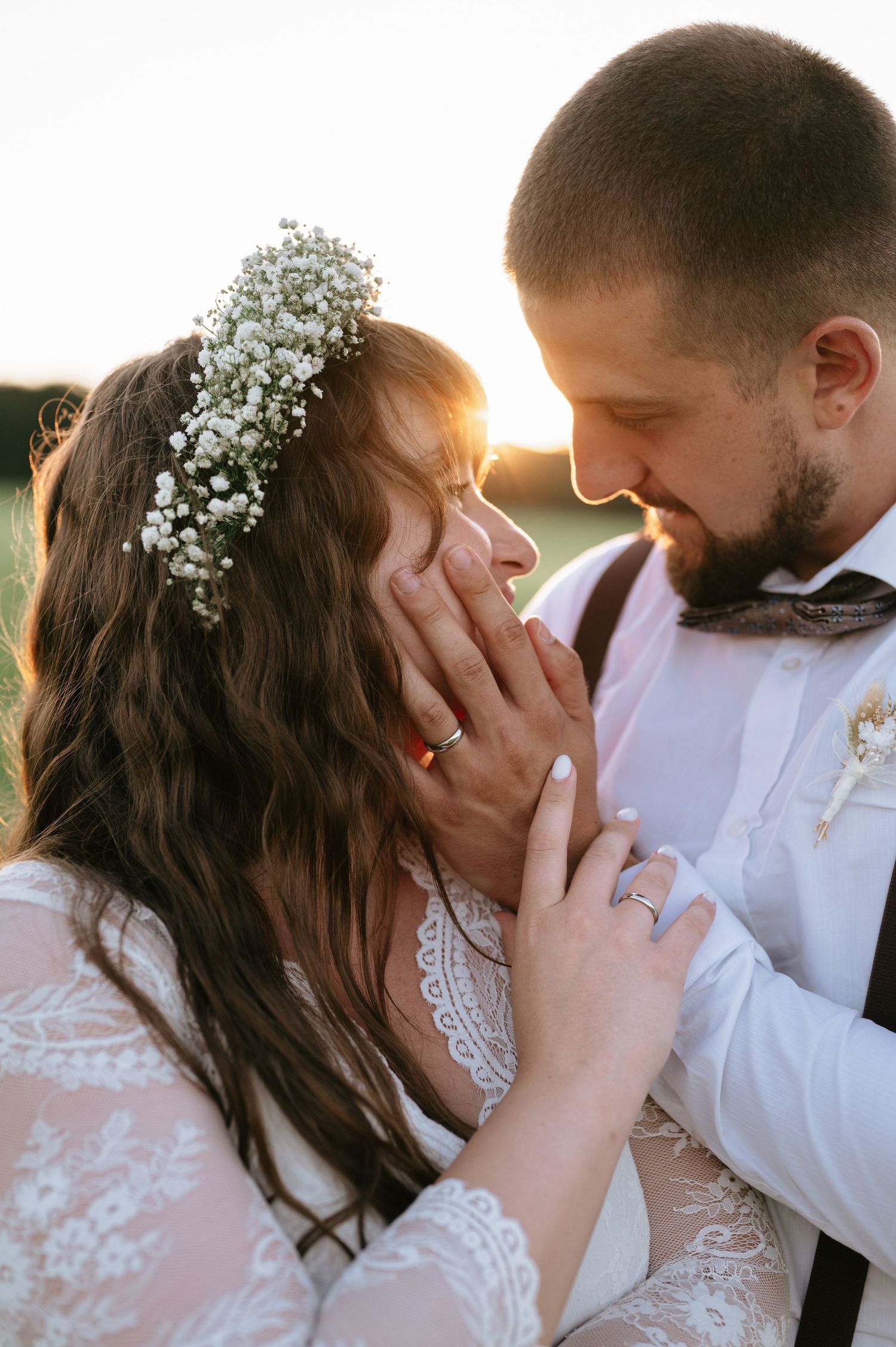 Tender wedding moment captured during sunset with delicate floral details.