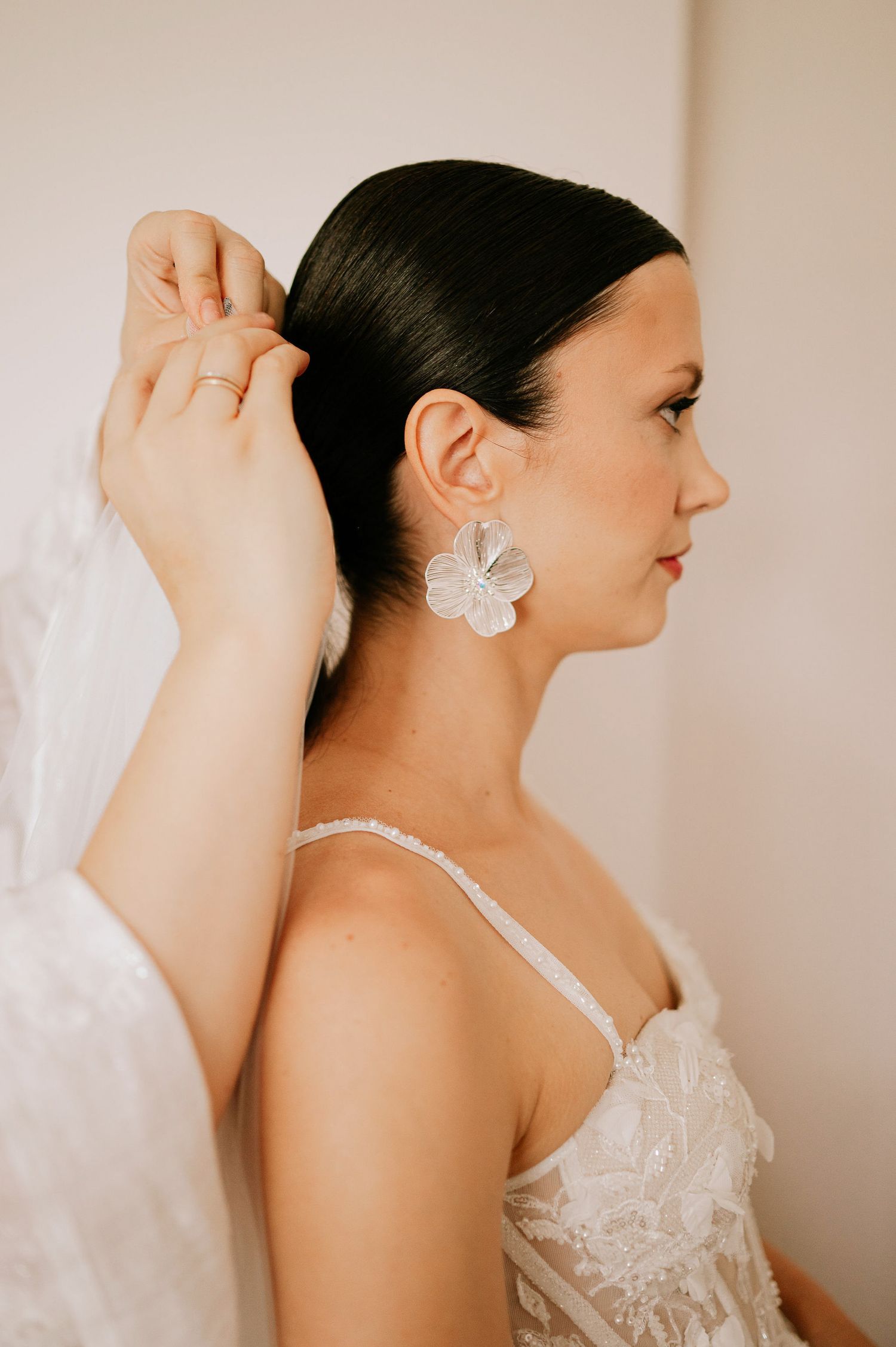 Close-up details of a bride's hair accessory and lace dress straps.