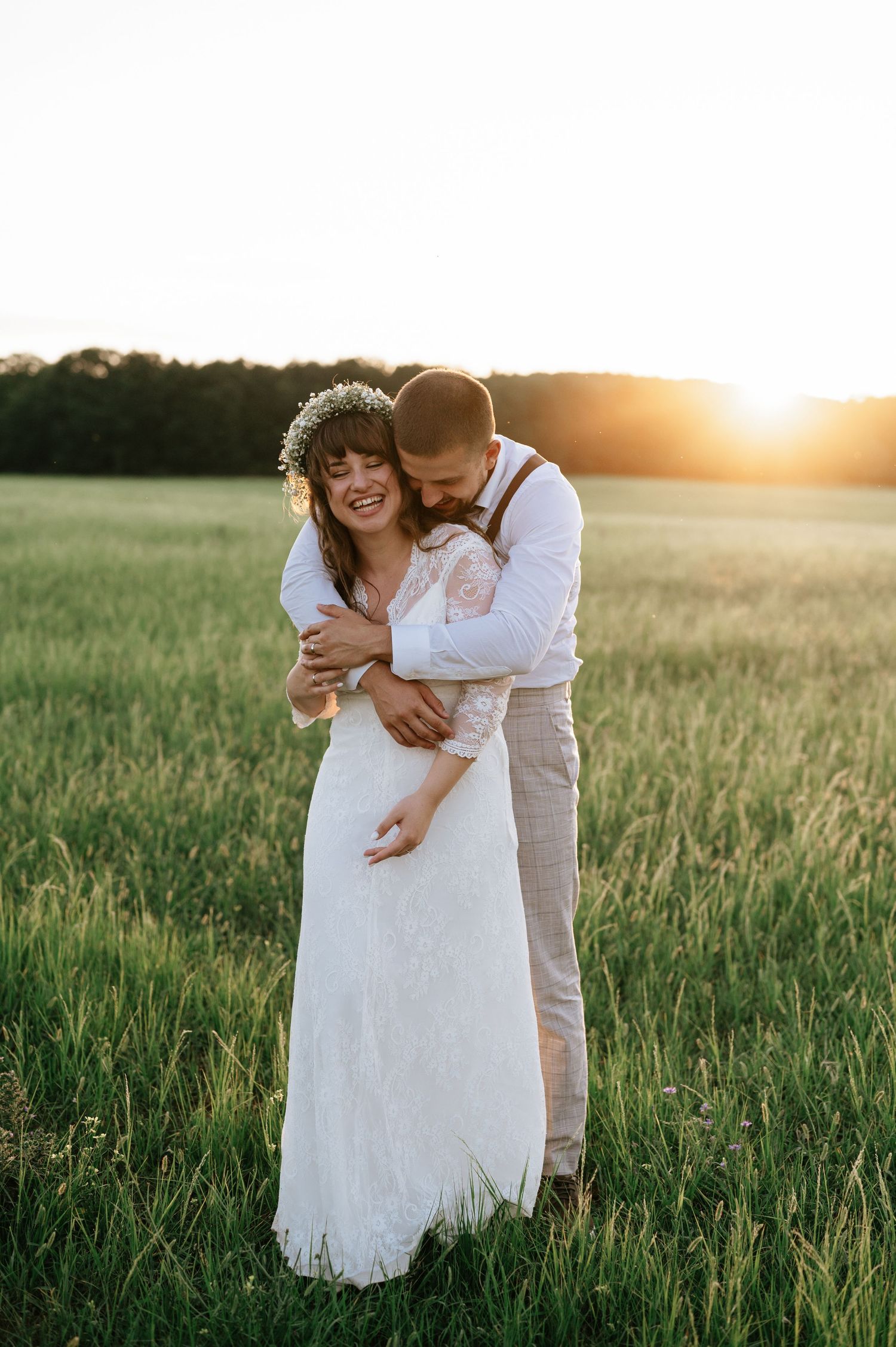 A tender moment between newlyweds in a sunlit field with flower crown details.