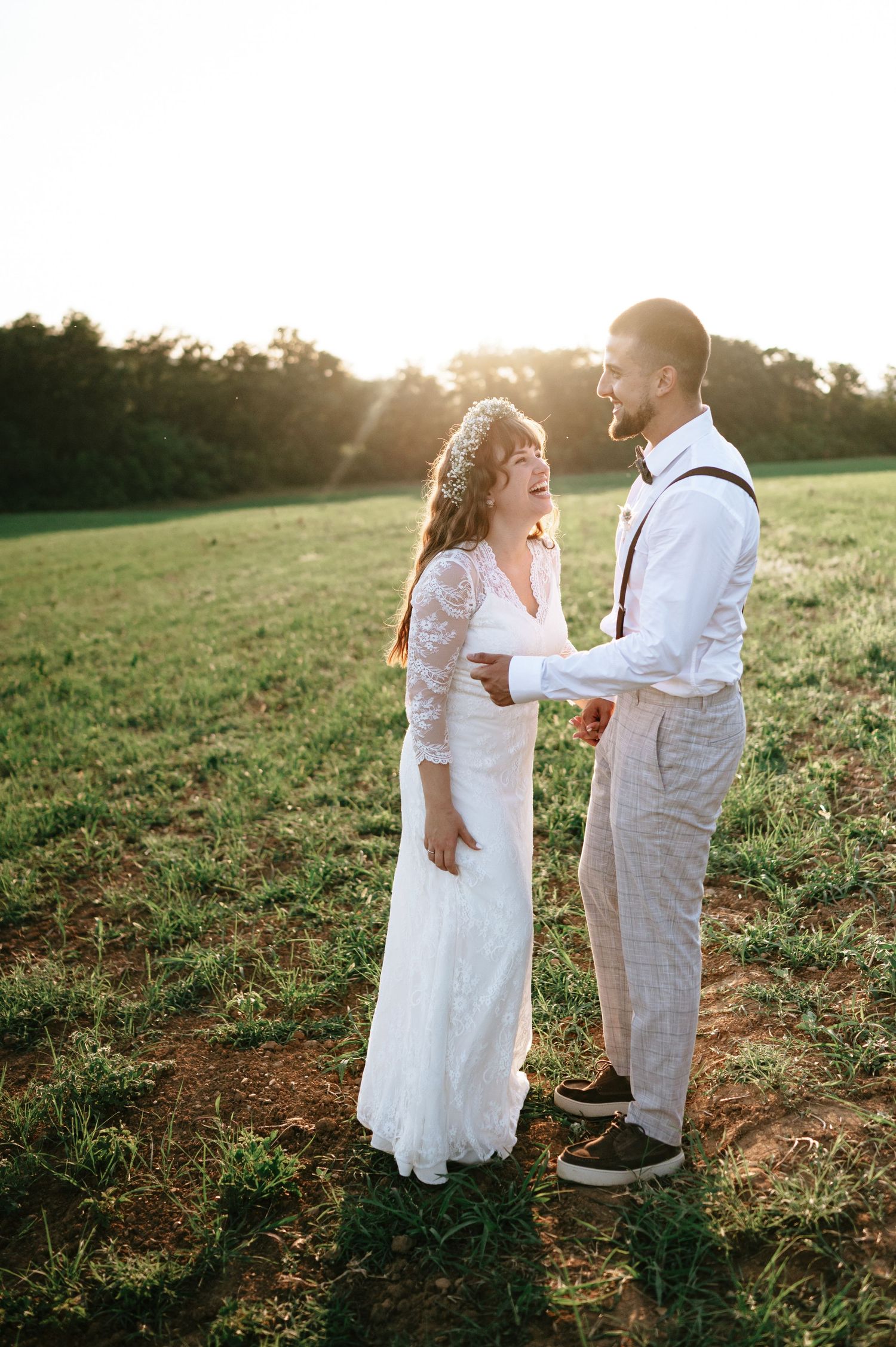 Candid wedding photos of couple walking through field during golden hour.
