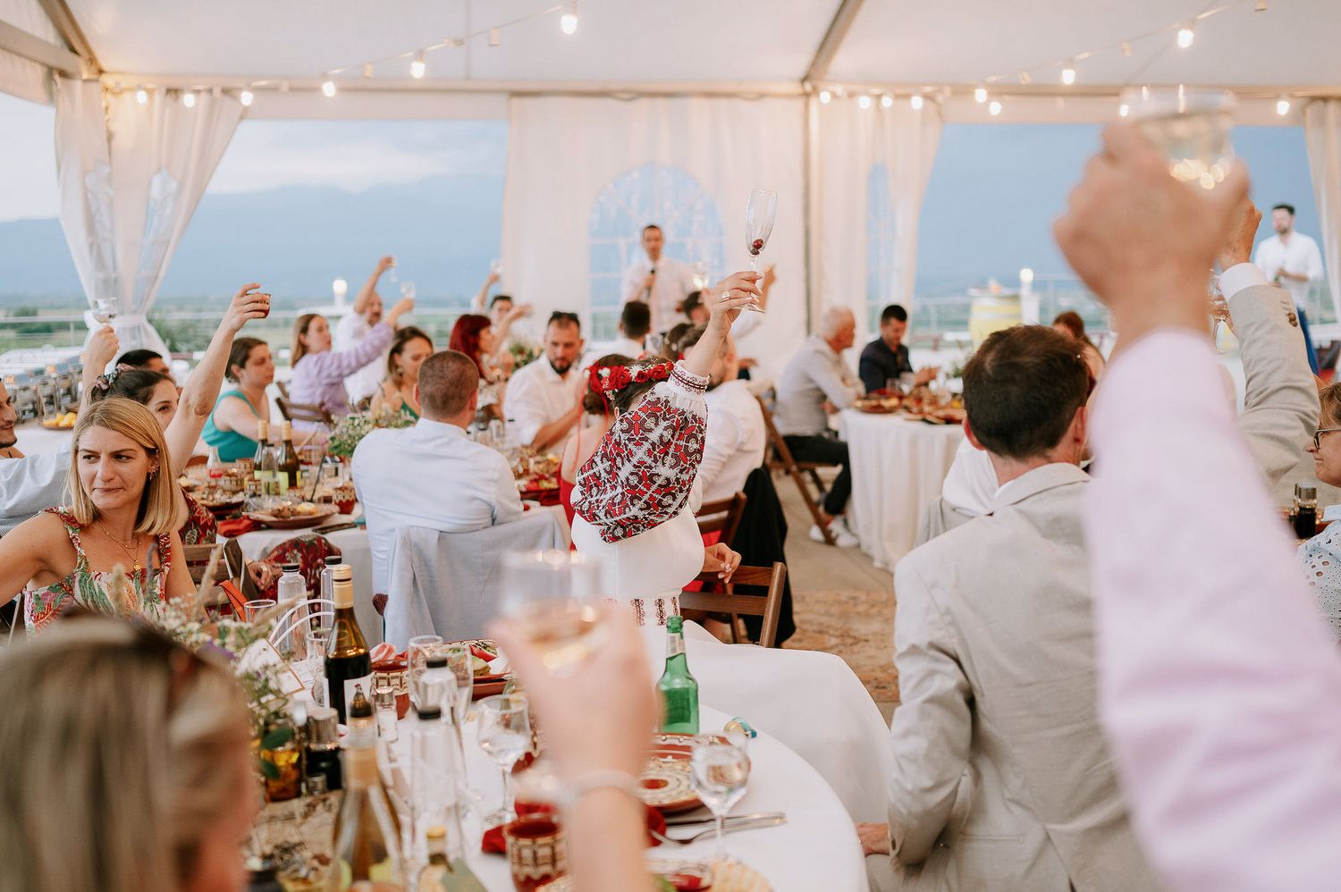 Joyful celebration with guests raising glasses during wedding reception toasts.