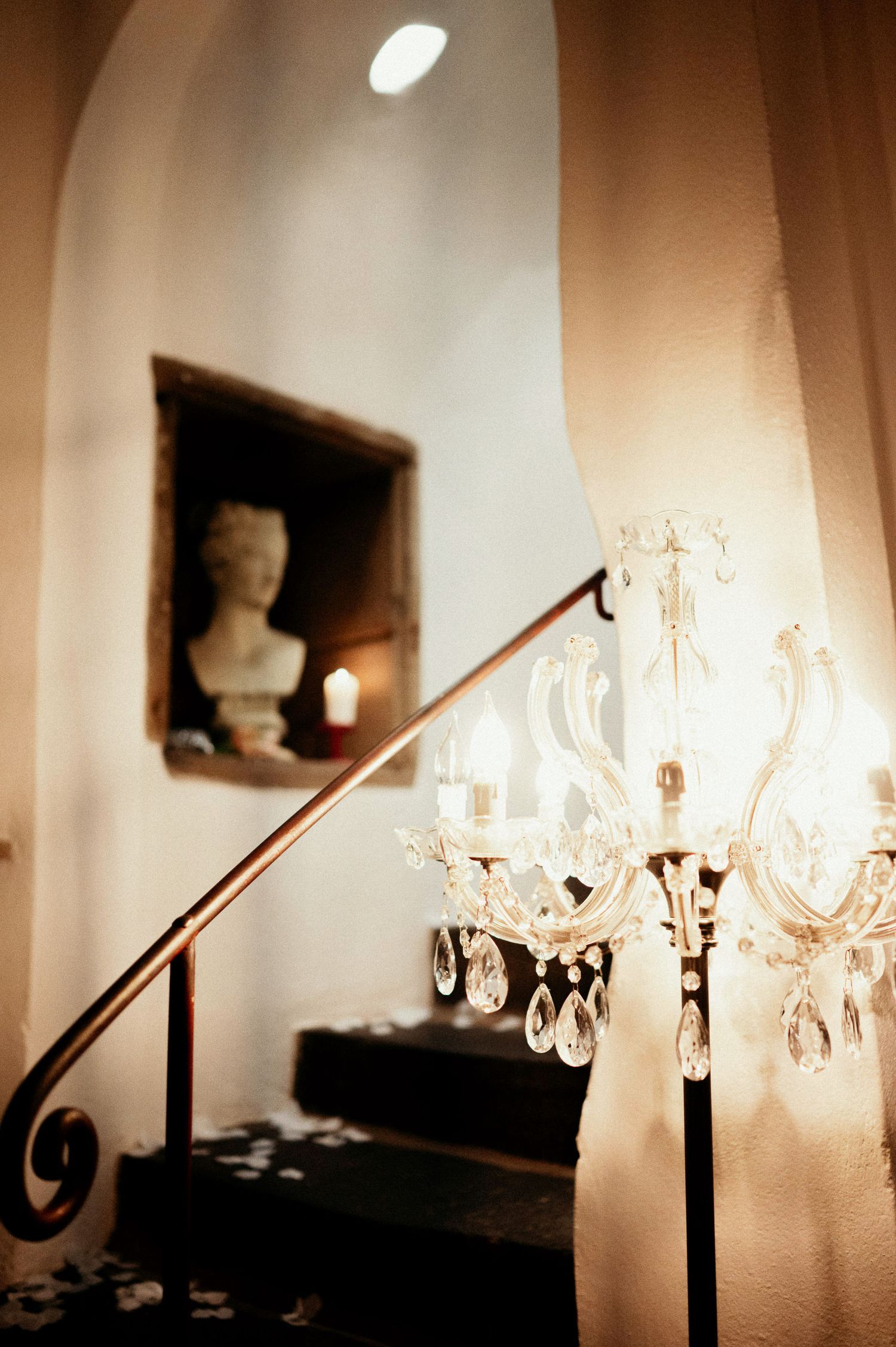 Crystal chandeliers line a white corridor creating an elegant ambiance with soft lighting.