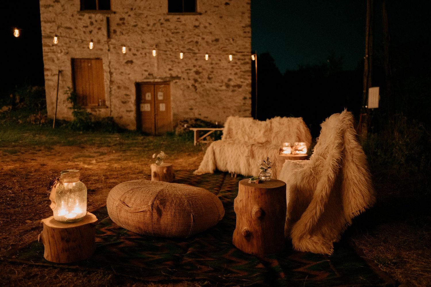 Historic stone building facade illuminated by string lights and lanterns at night.