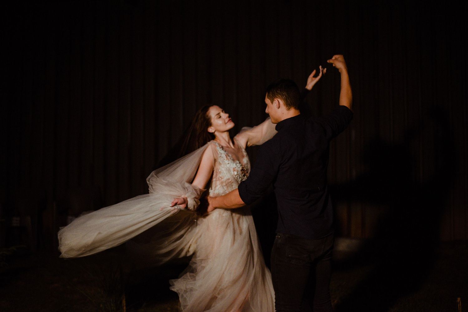 Artistic black and white wedding photos showing graceful dance-like movements in a dark, intimate setting.