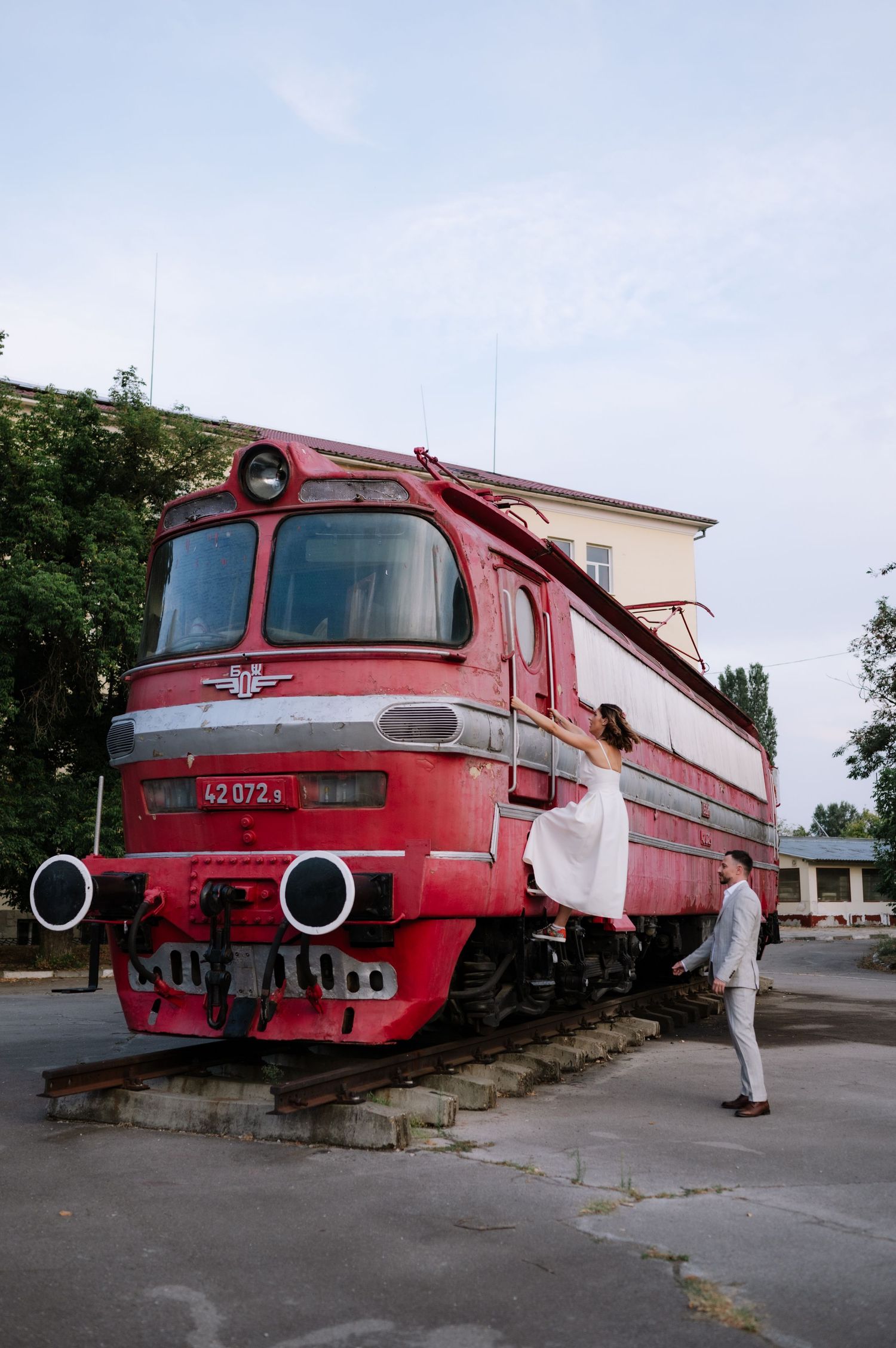 Four sequential photos show a vintage red locomotive train from different angles at a railway station platform.