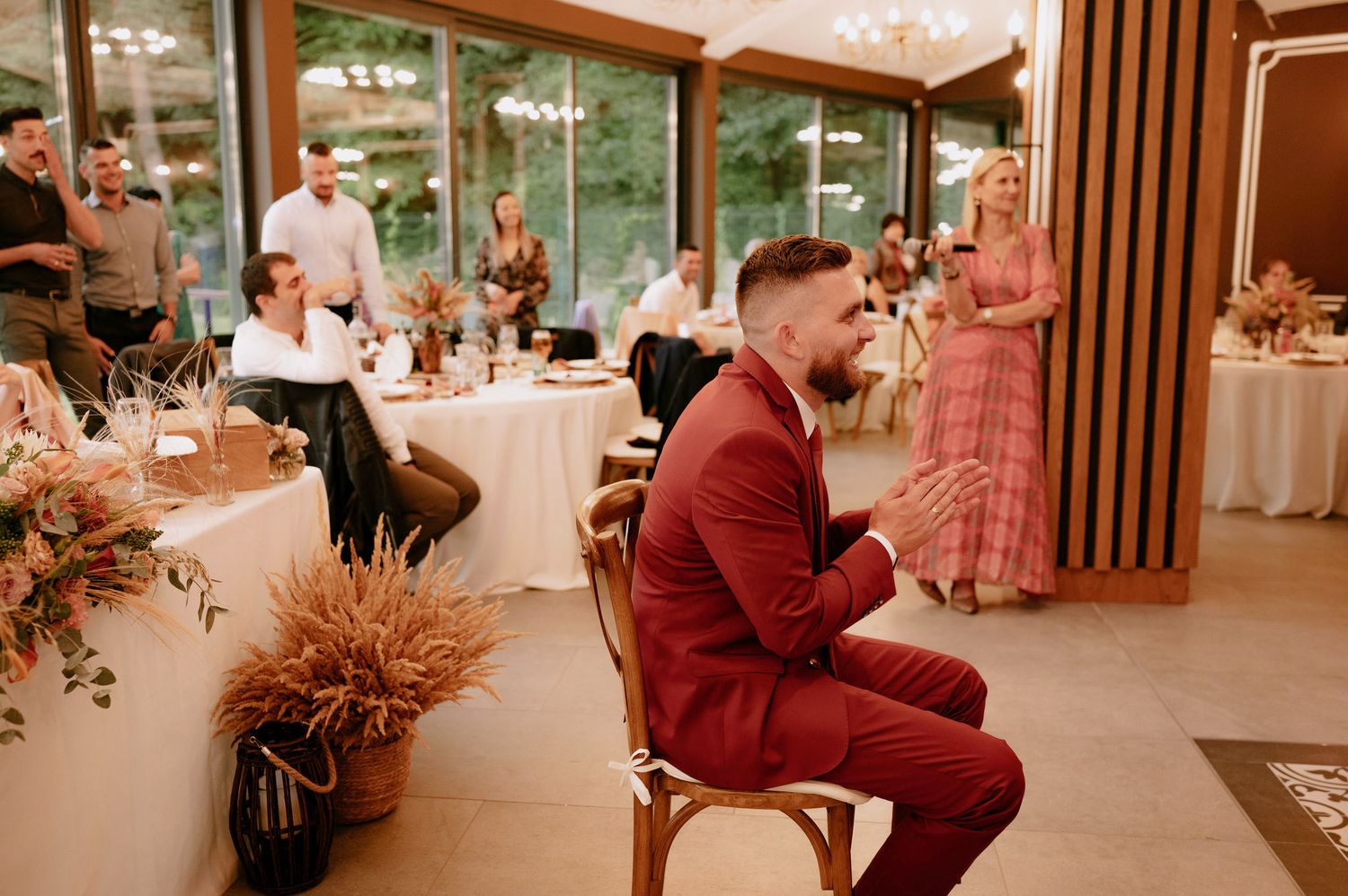 A romantic wedding reception venue with warm lighting, wooden dividers, and elegant table settings.