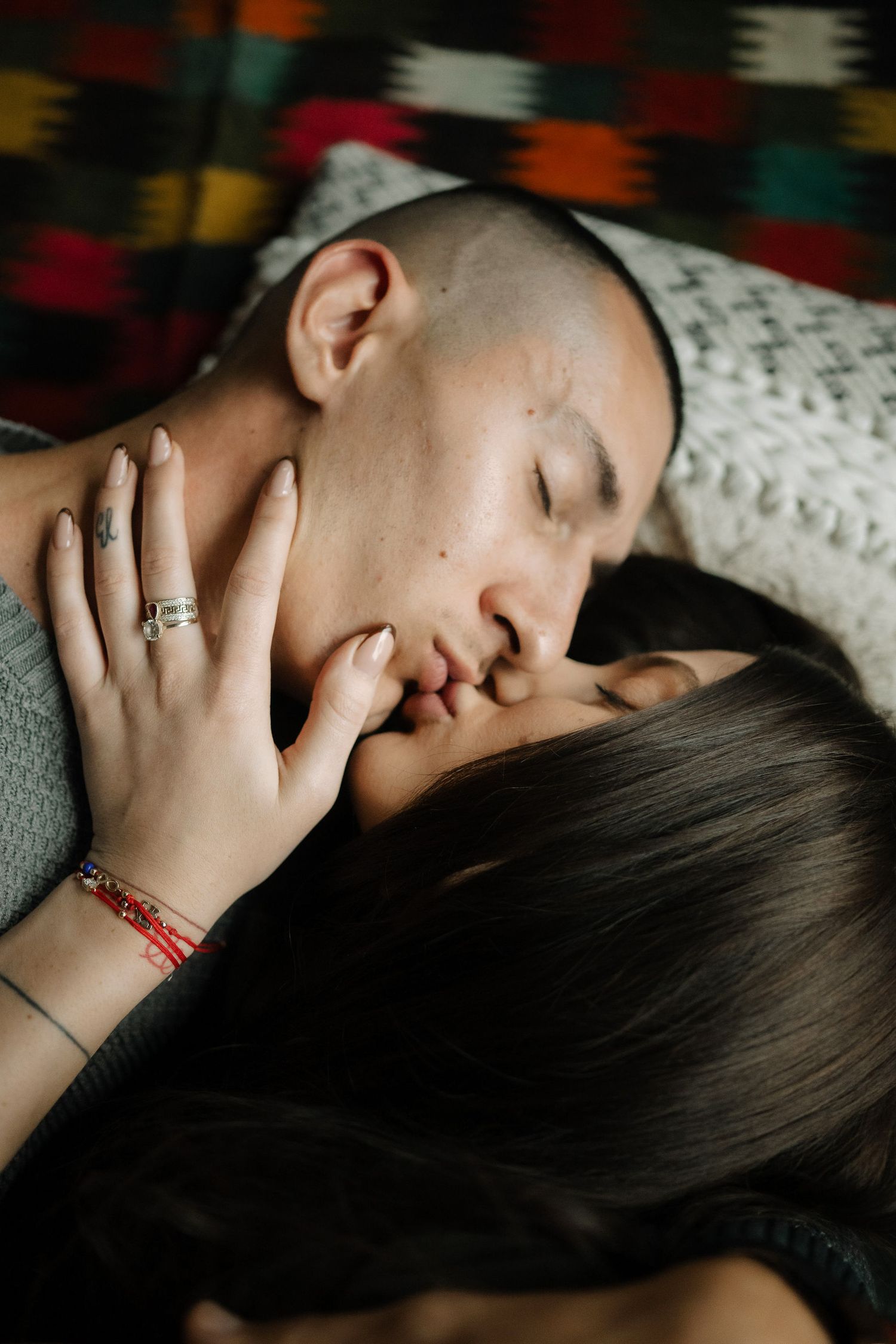 A couple shares a tender moment while resting together on a couch with gray cushions.
