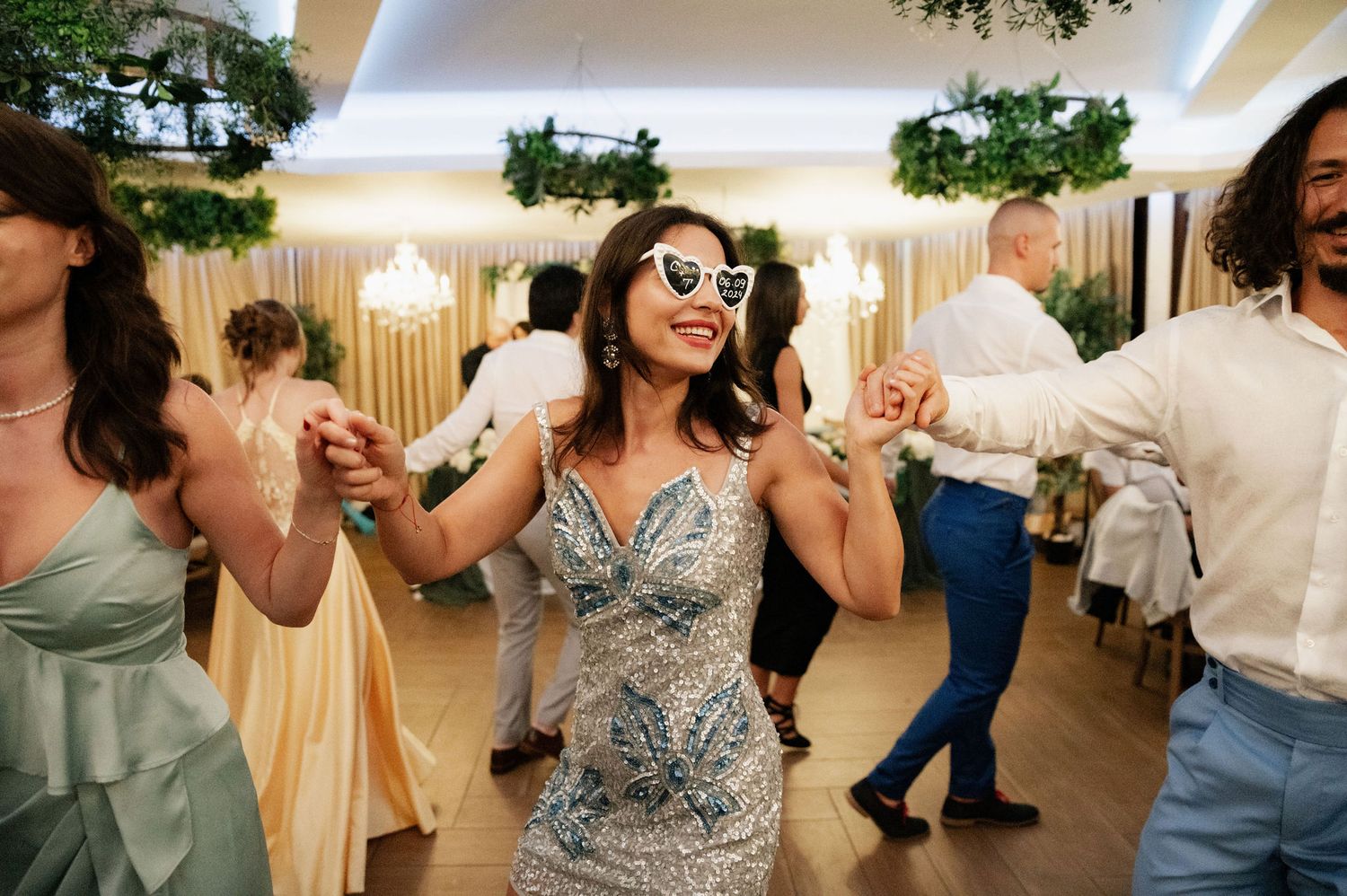 Wedding guests dance together during a lively reception celebration in an elegant indoor venue.
