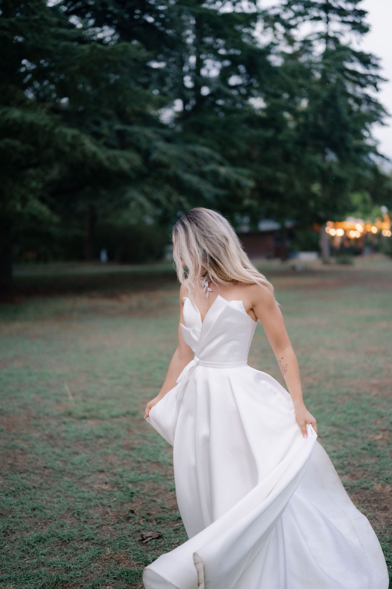 A white bridal gown spins and flows in a natural outdoor setting with evergreen trees in the distance.
