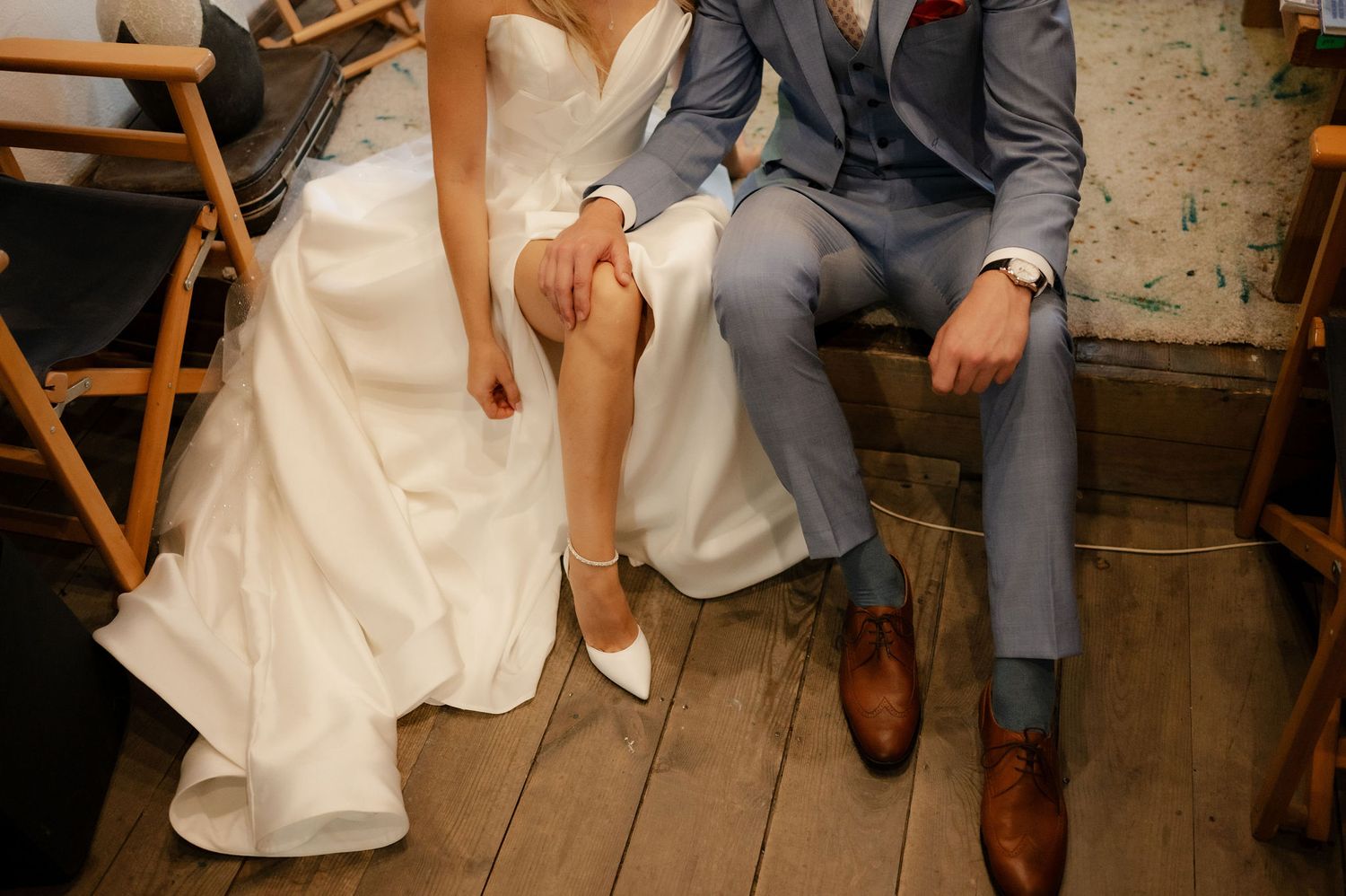 A close-up view of formal shoes and wedding attire on a wooden floor during a celebration.